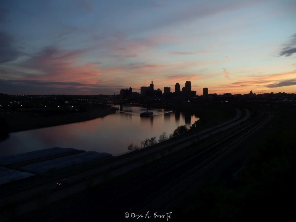 View 426 - silhouetted urban area above calm river reflecting blue sky and purple clouds at dusk, Humanity, St Paul Minnesota USA, Spring 2015