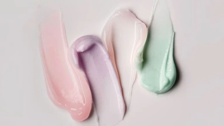 Creams in pink, purple, white, and green colors spread on a flat surface.