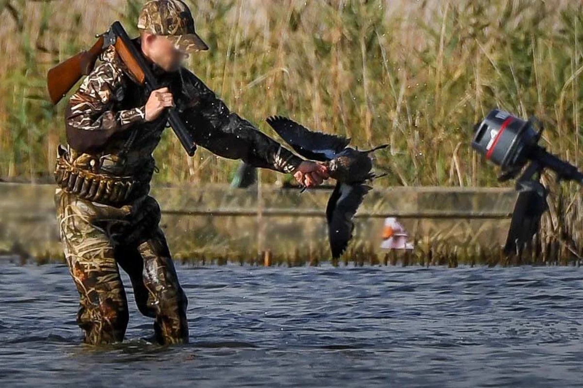 A duck hunter with a dead duck.