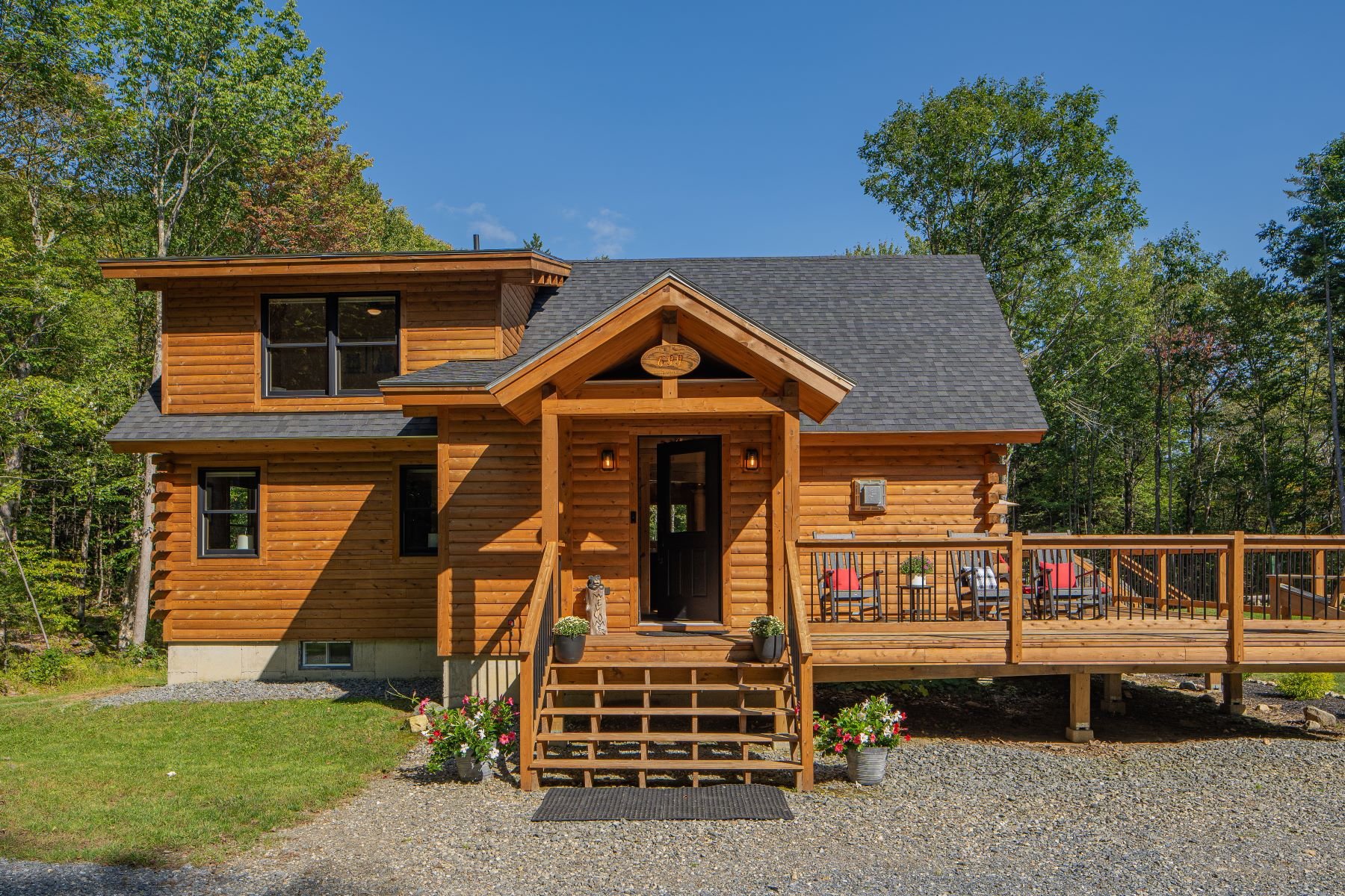 The covered front porch offers a warm welcome with its sturdy log posts, wide steps, and lantern-style sconces.