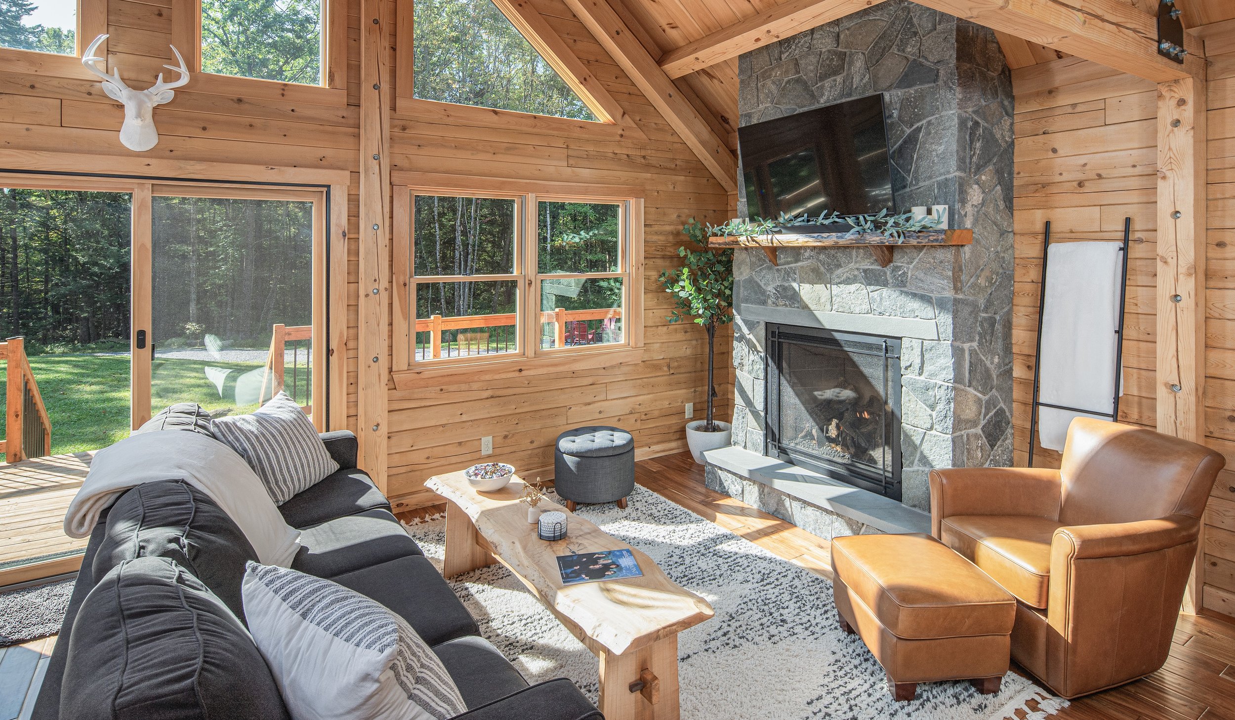 Natural elements like wood, stone, and leather pair effortlessly with neutral tones and simple furnishings. Bathed in natural sunlight, this living room is a bright, modern take on classic lodge style.
