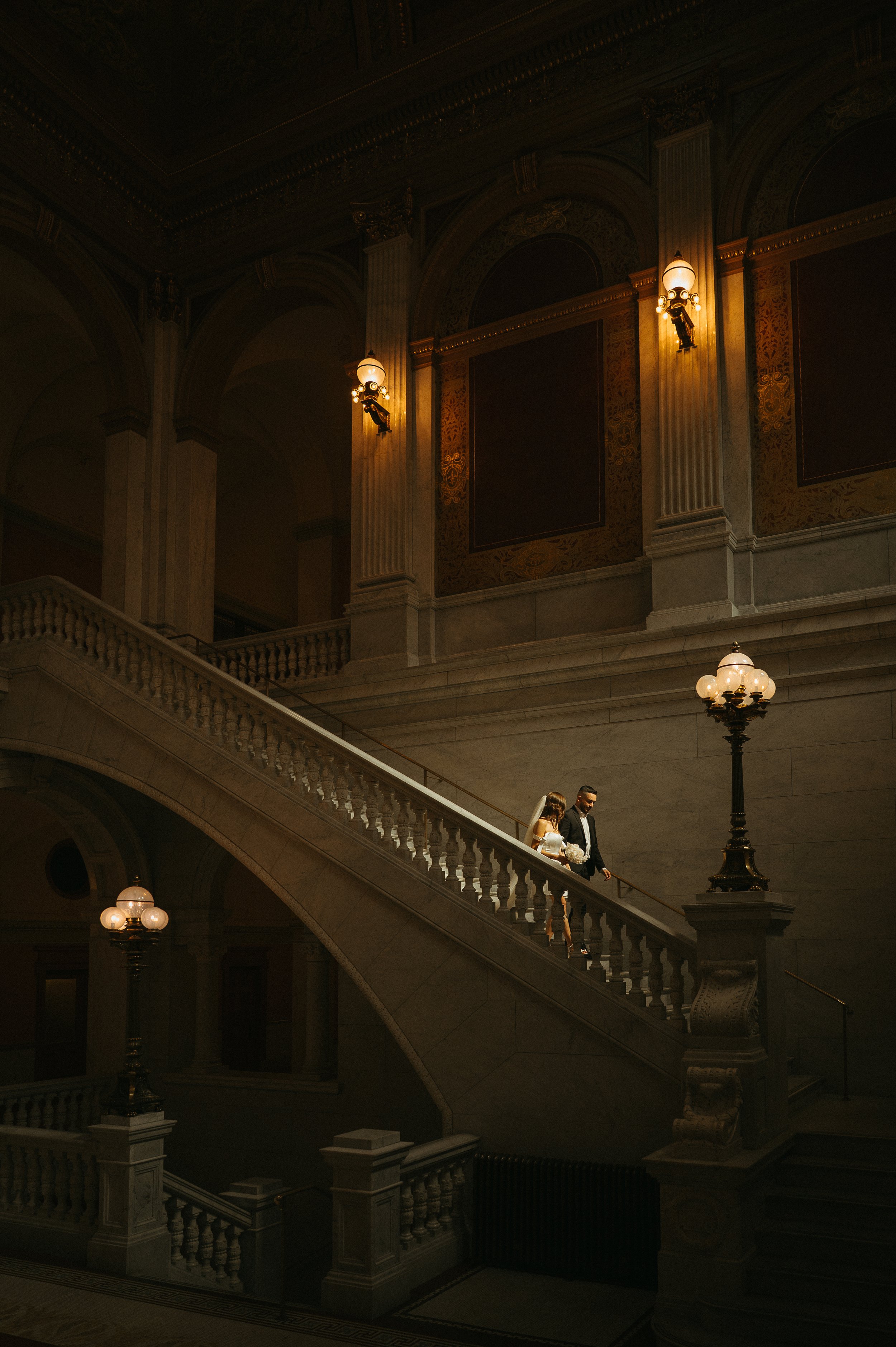 Bride and groom walking down a grand staircase at the Ohio Statehouse following their courthouse elopement ceremony..