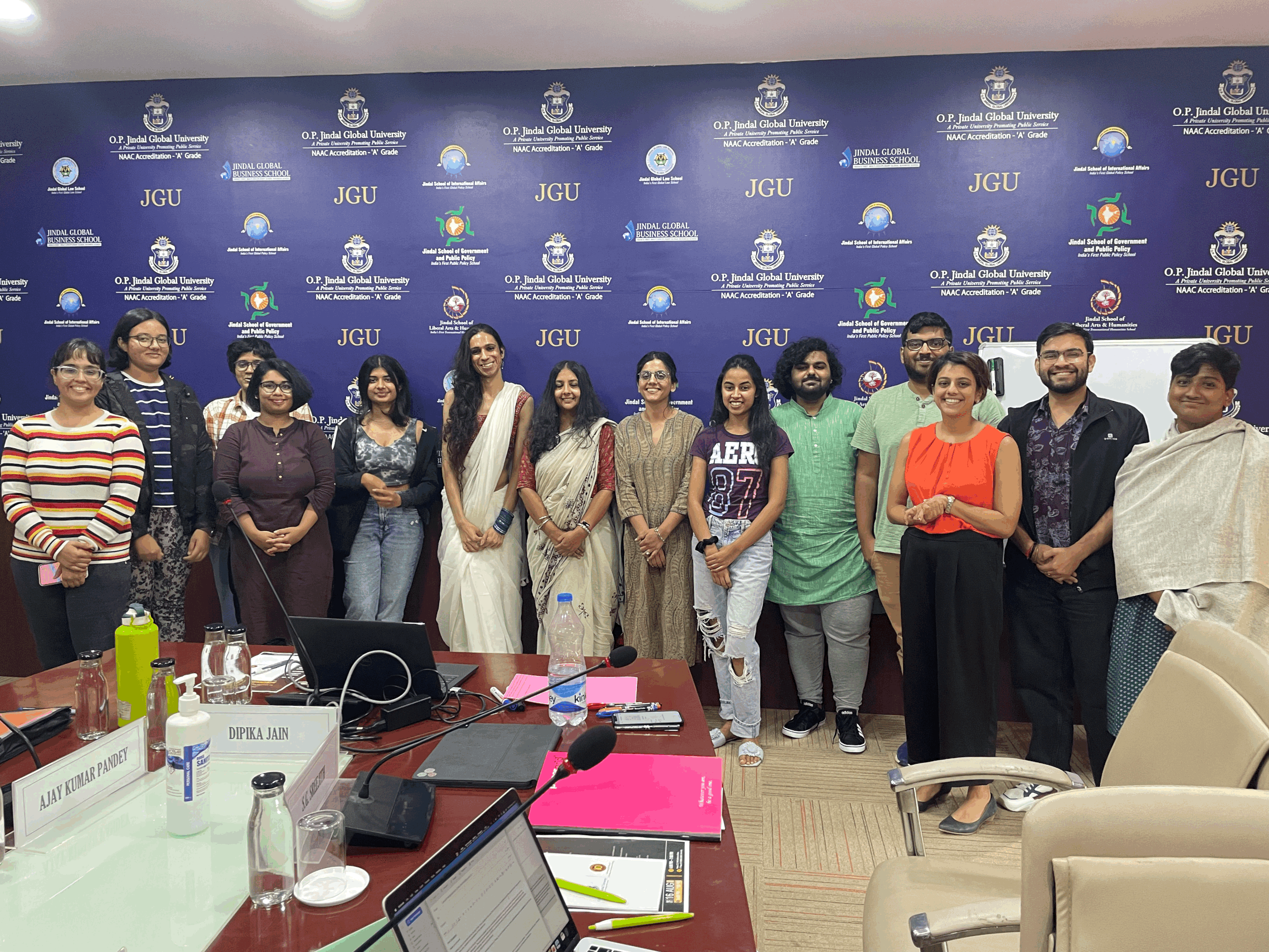 A group of persons posing for a picture from a conference room, all with big bright smile