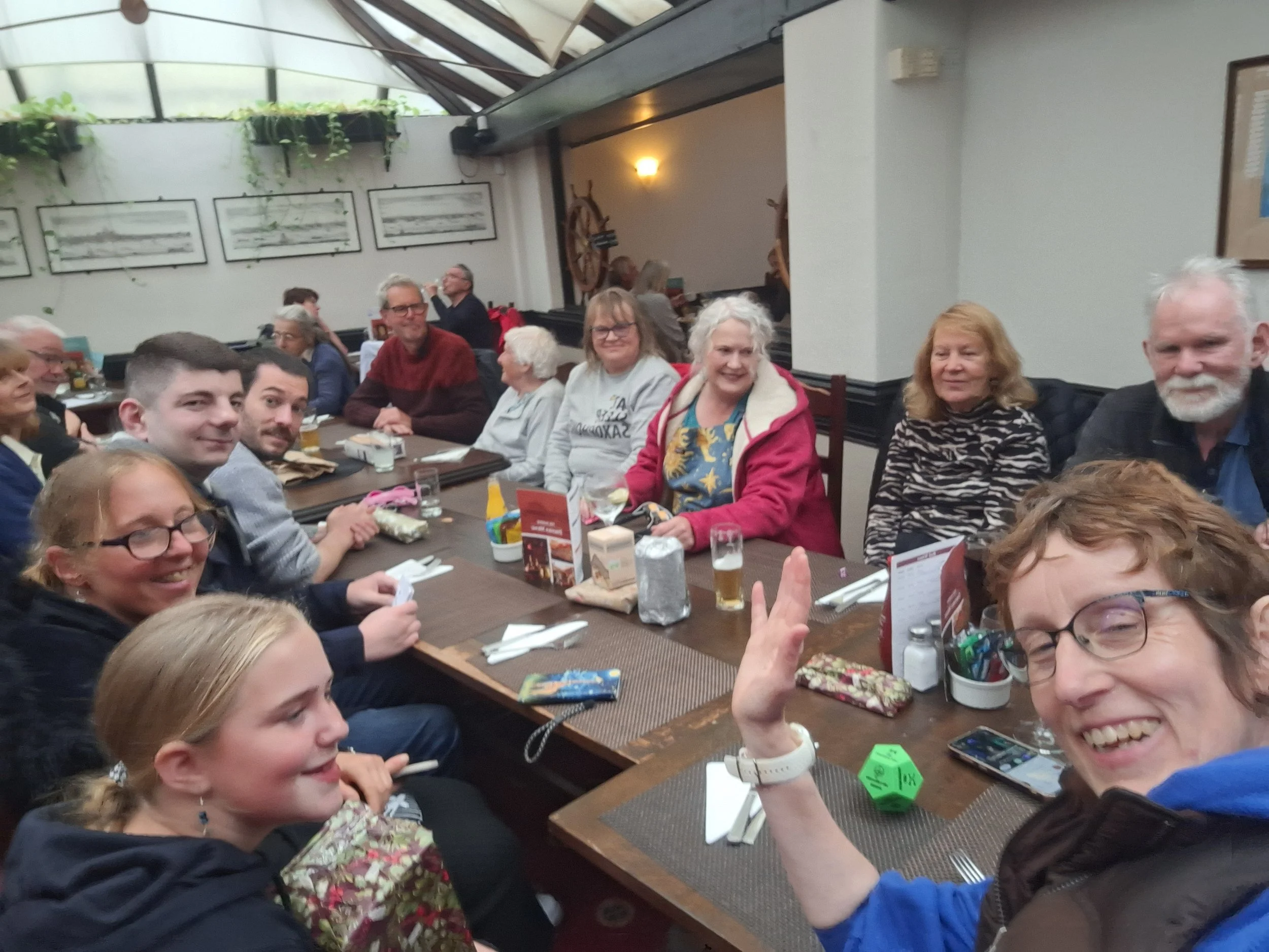 Group of cross generation people male and female sit in pub setting, there is a dice and parcels a game of snatch is being played.
