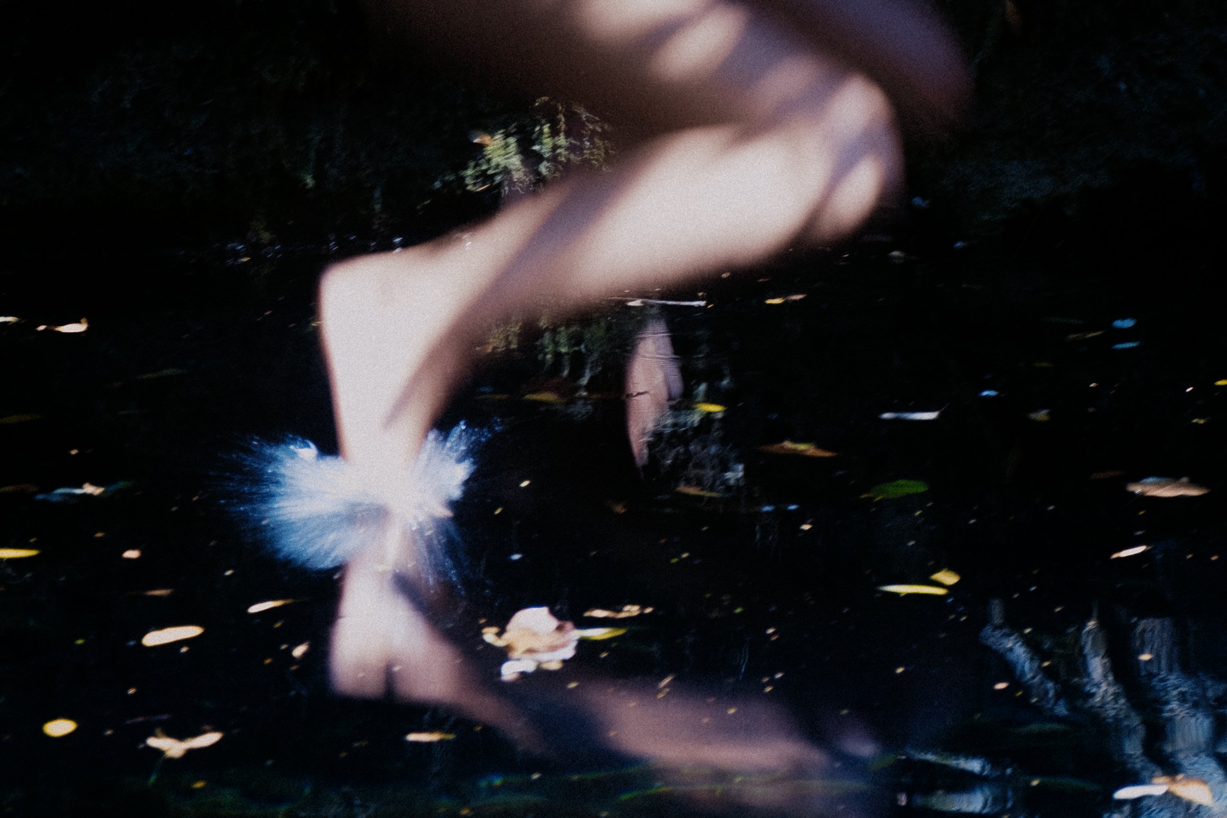 Blurred image of a person running through water, with splashes and reflections.