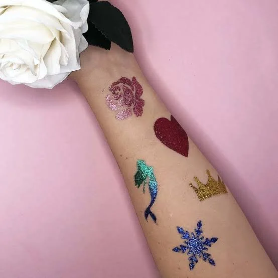 A forearm with several glitter tattoos.