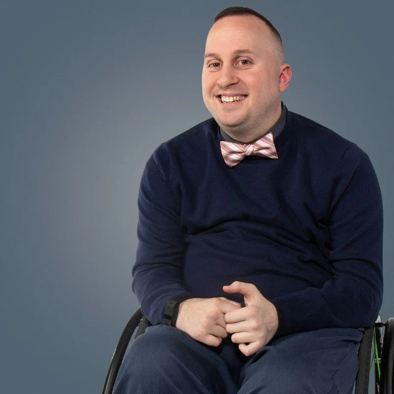 Smiling man wearing a bowtie and using a manual wheelchair