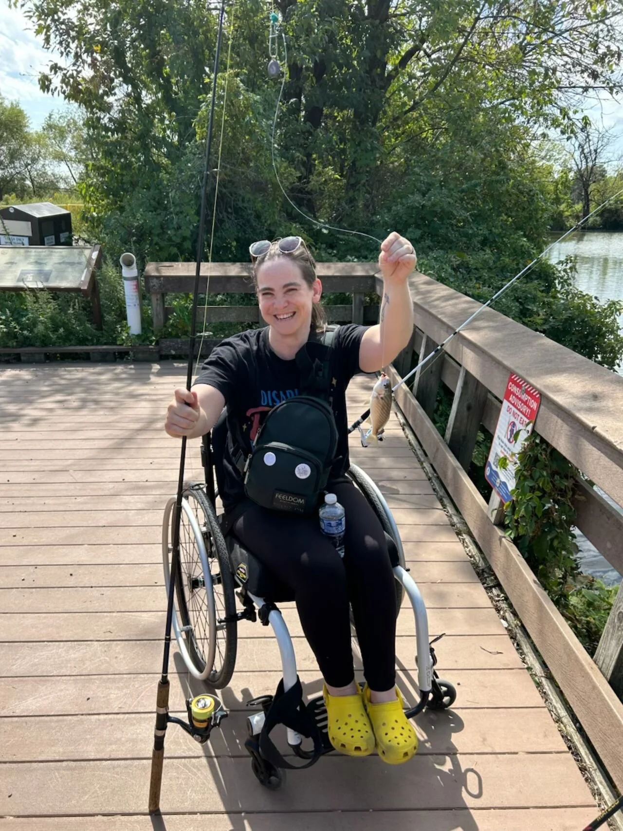 Izzy  uses her chair holds up the fish they caught on a wooden pier
