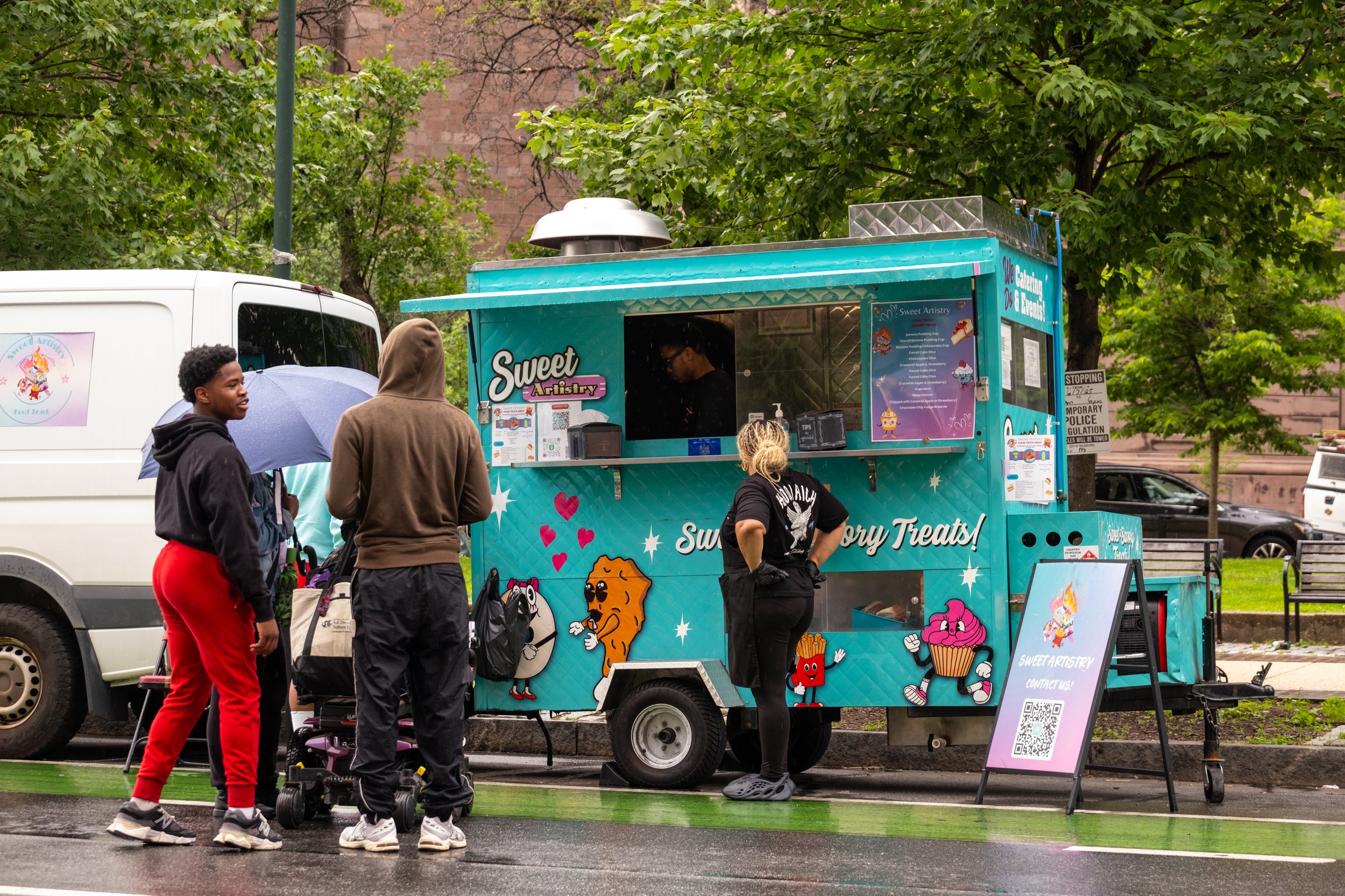 Brightly colored food truck with people standing in line.