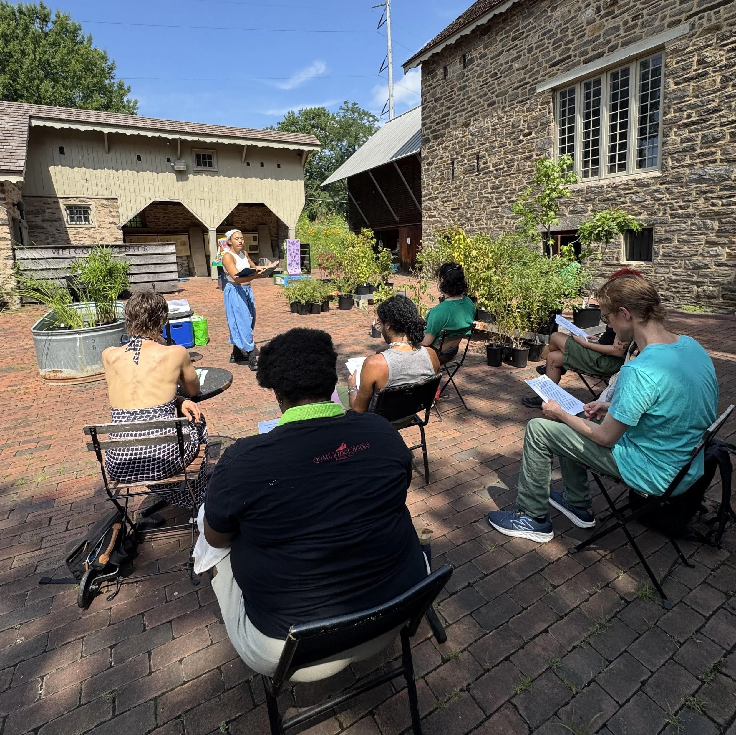 Participants of the World Building in Nature event are writing in an outdoor courtyard.
