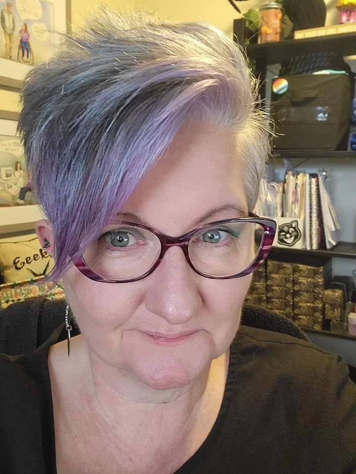 Smiling person with purple and gray hair.