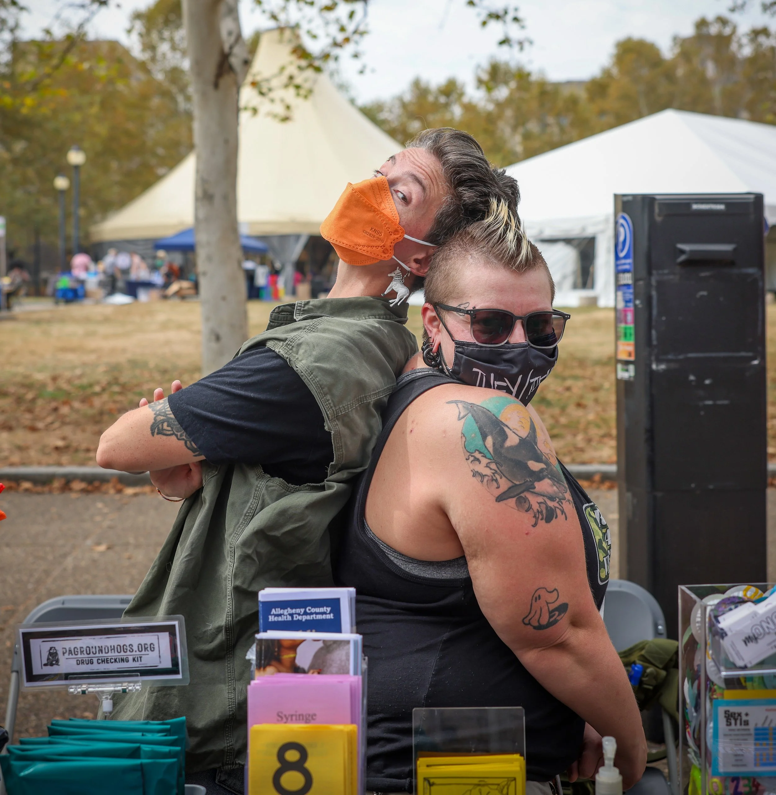Two tattoed people standing back to back mugging for camera