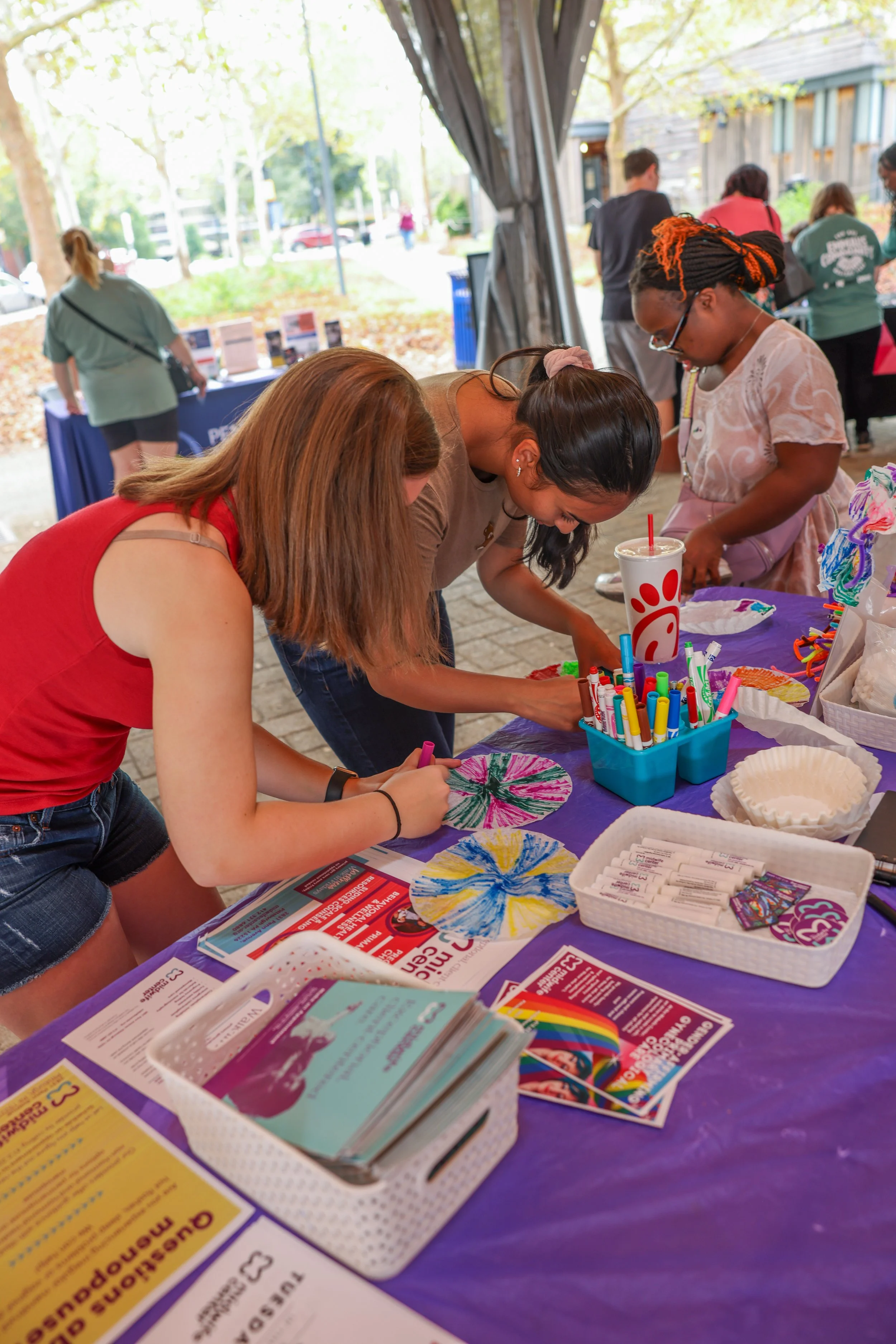 Woman and children doing craft activities at a vendor booth 