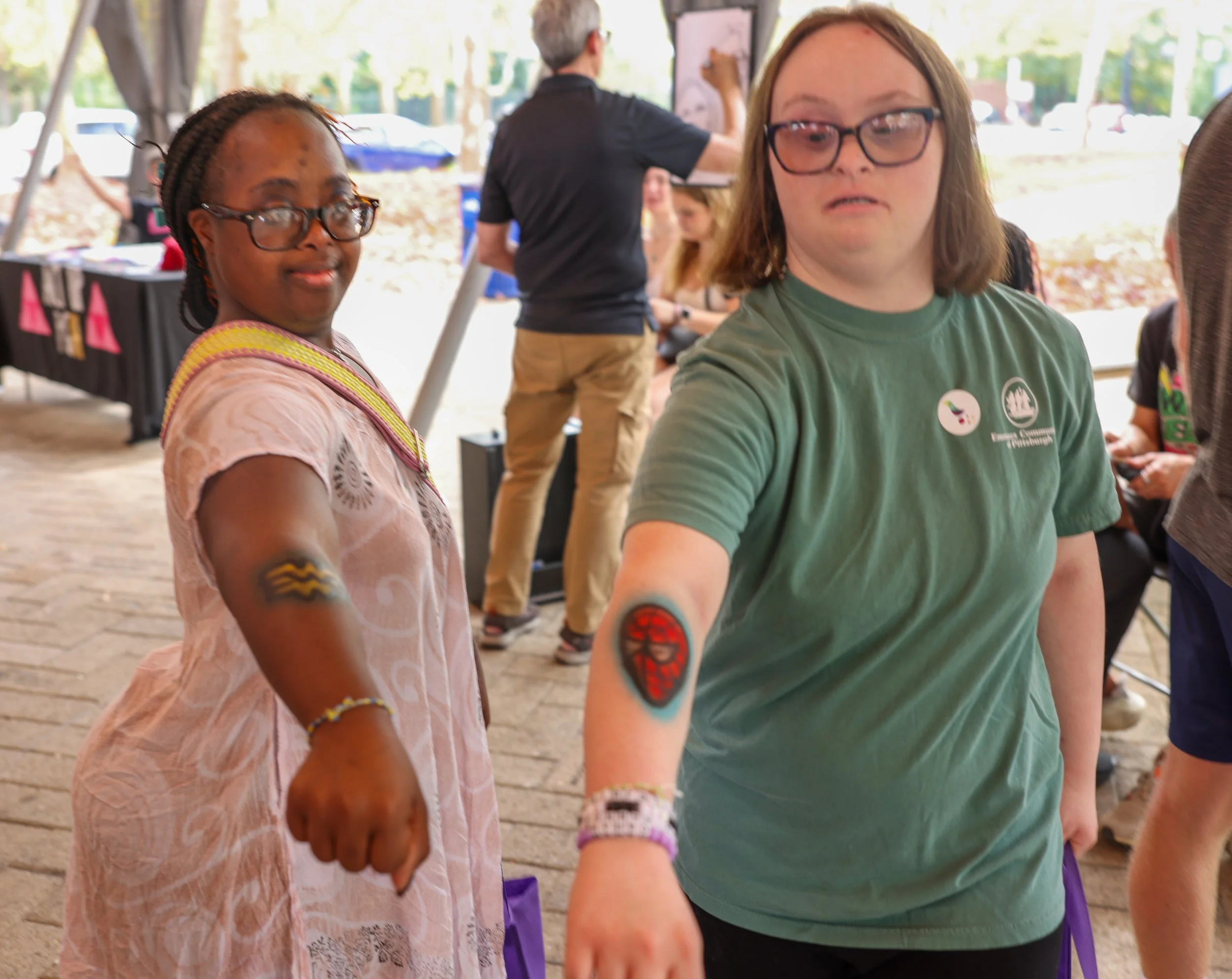 Two young people with Down syndrome showing off temporary tattoos on their arms