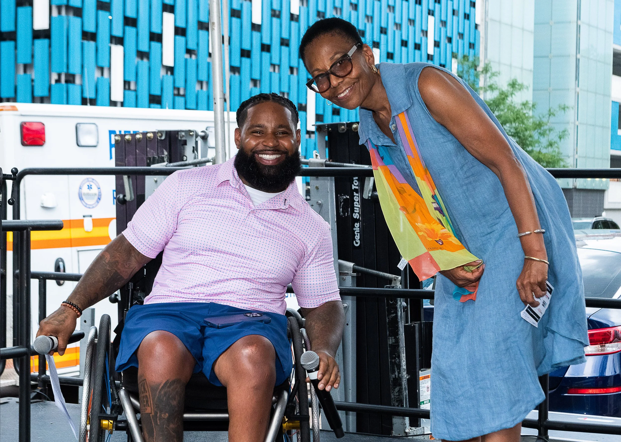 Wes Hamilton in pink shirt in his wheelchair, guest emcee, with Marcia Martin, of Highmark Wholecare beside him at Pittsburgh event