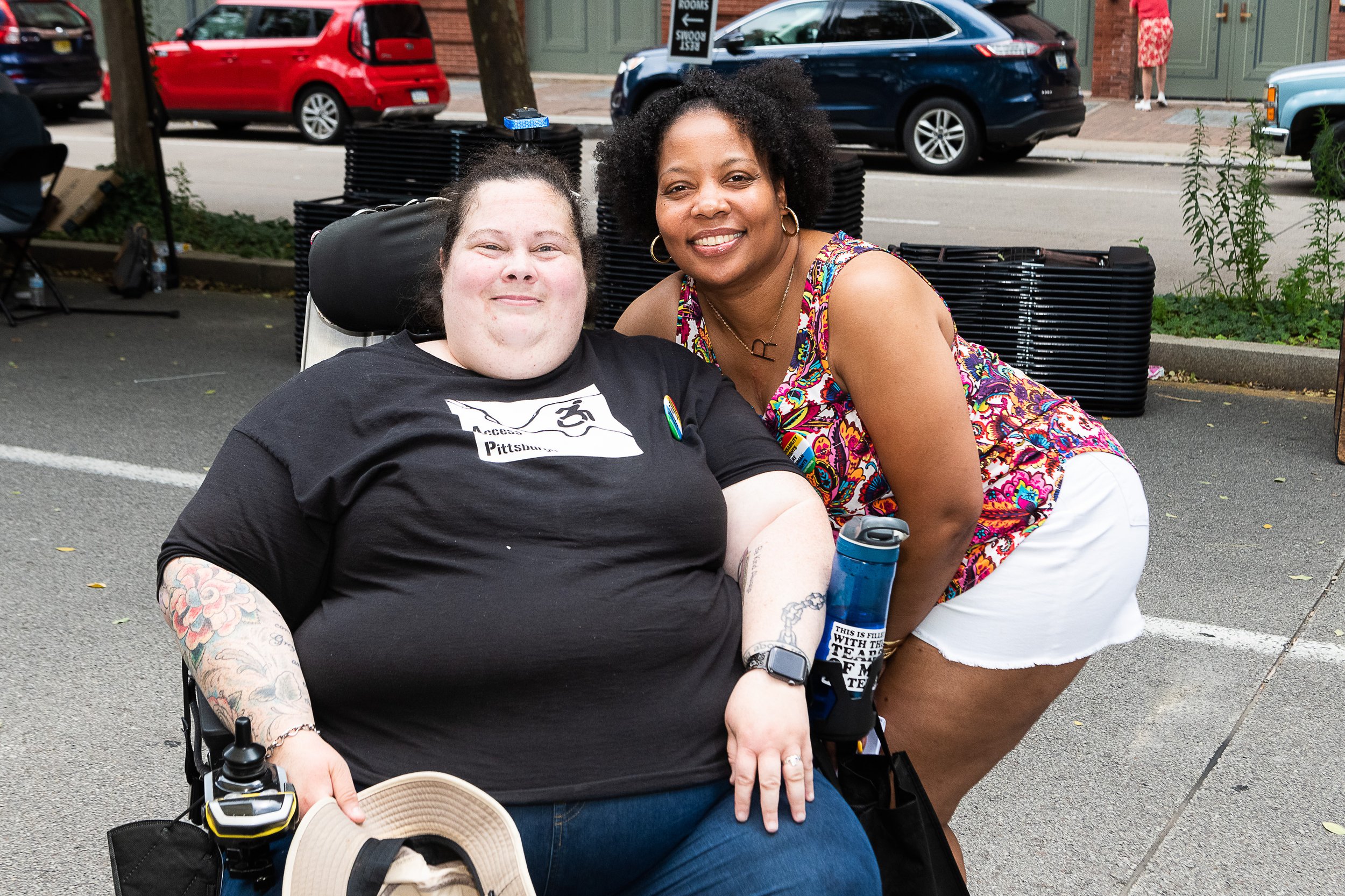 Alisa, a wheelchair user, poses with a friend standing beside her.