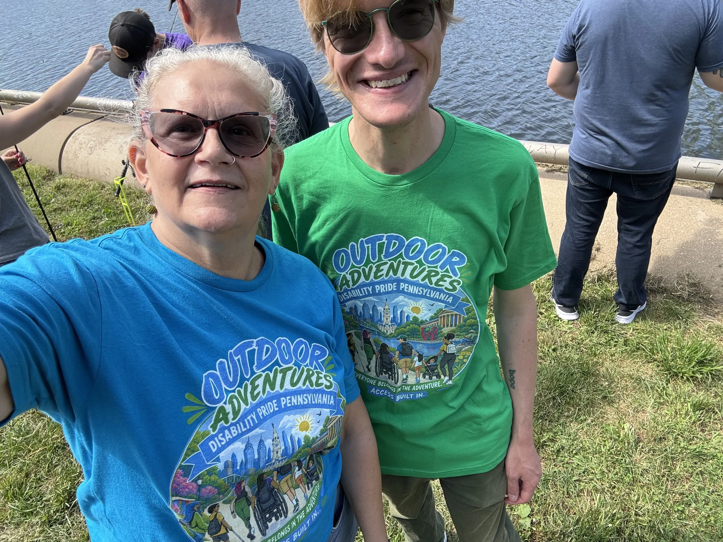 Two people wearing Outdoor Adventure tees in blue and green.