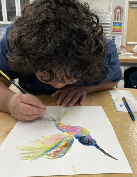 Student painting a watercolor picture of a hummingbird