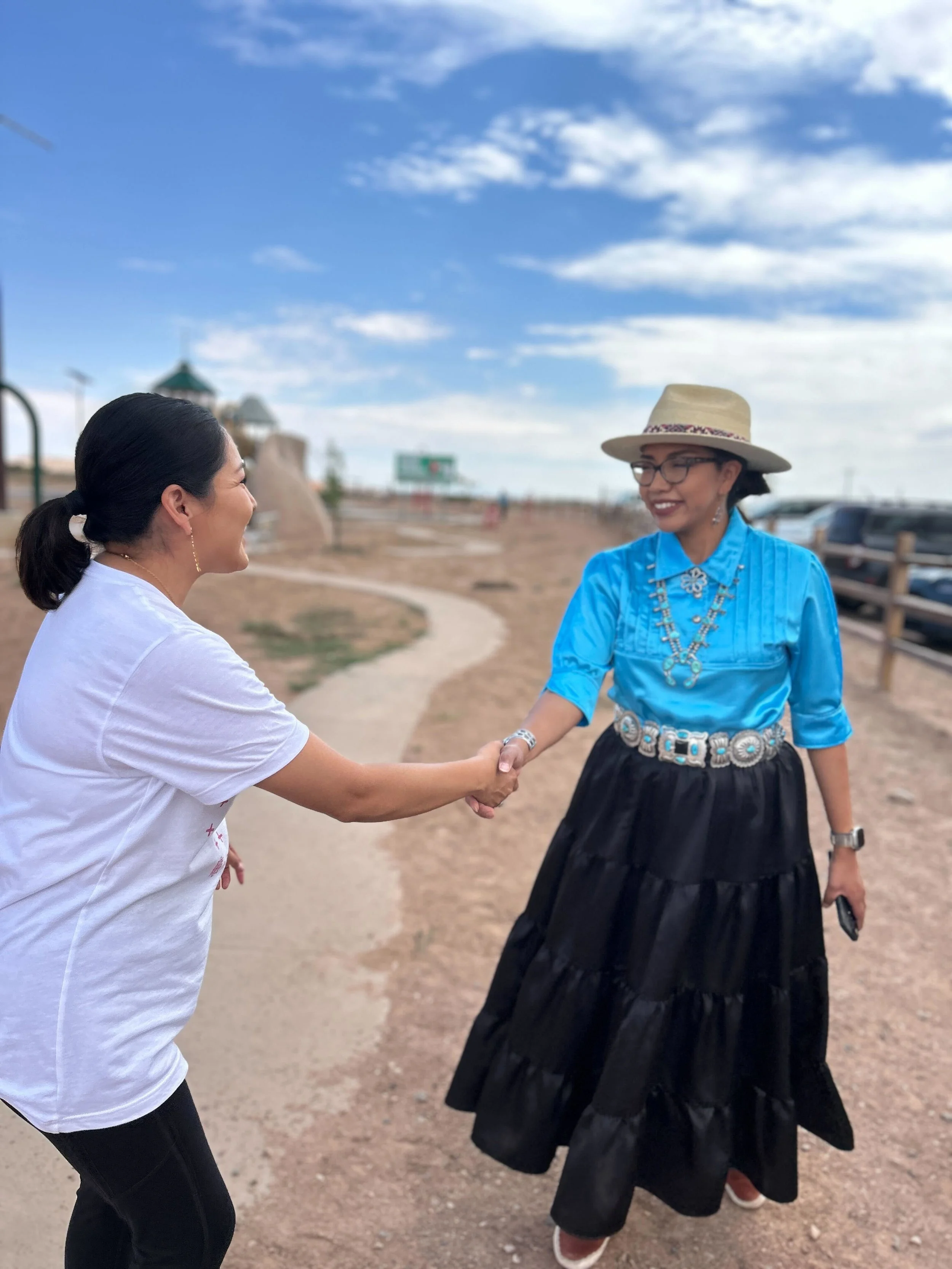 Photo of two Native American Women shaking hands at a local voter registration event.