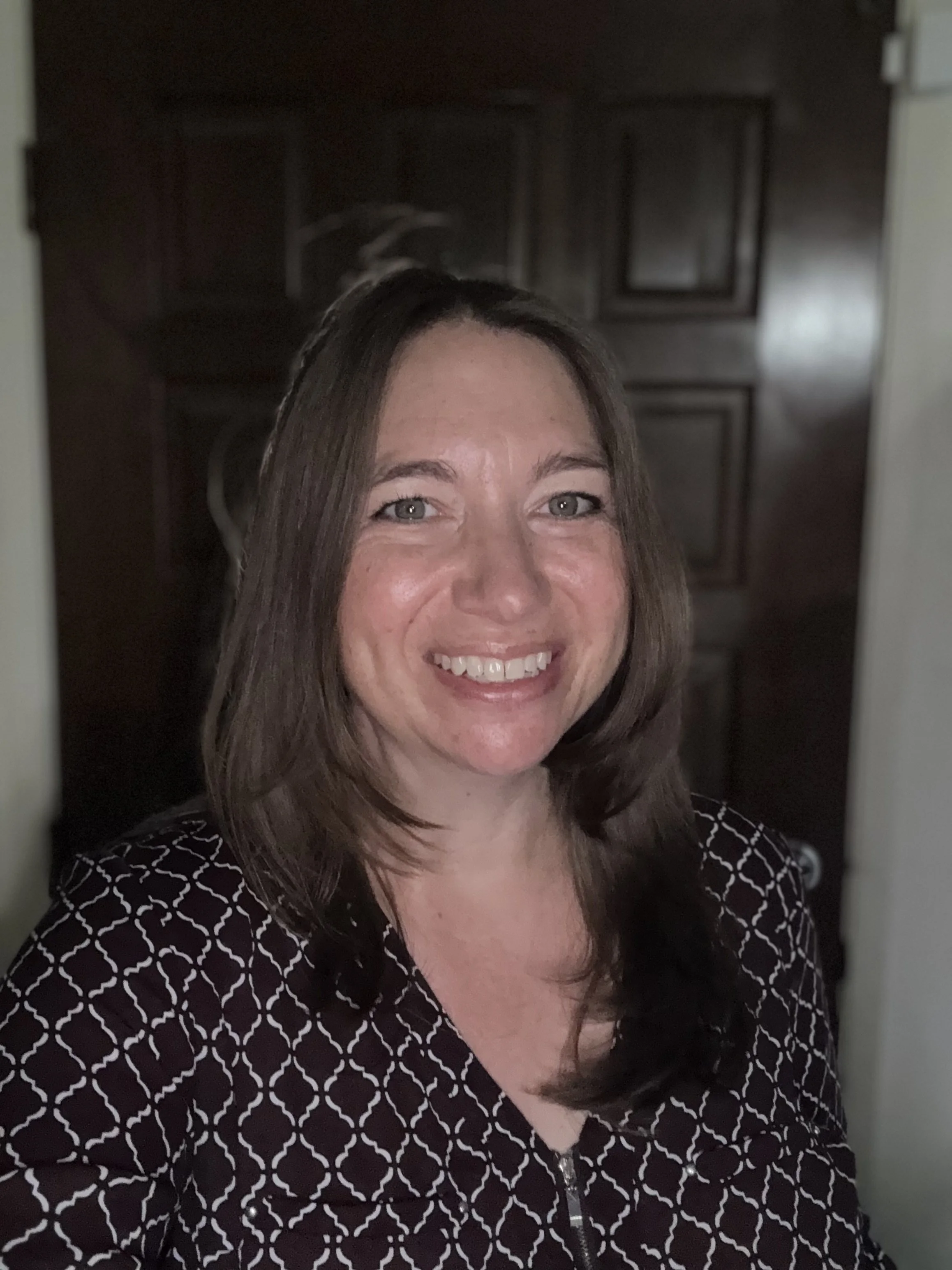 Caucasian female, brown hair framing her face with purple shirt