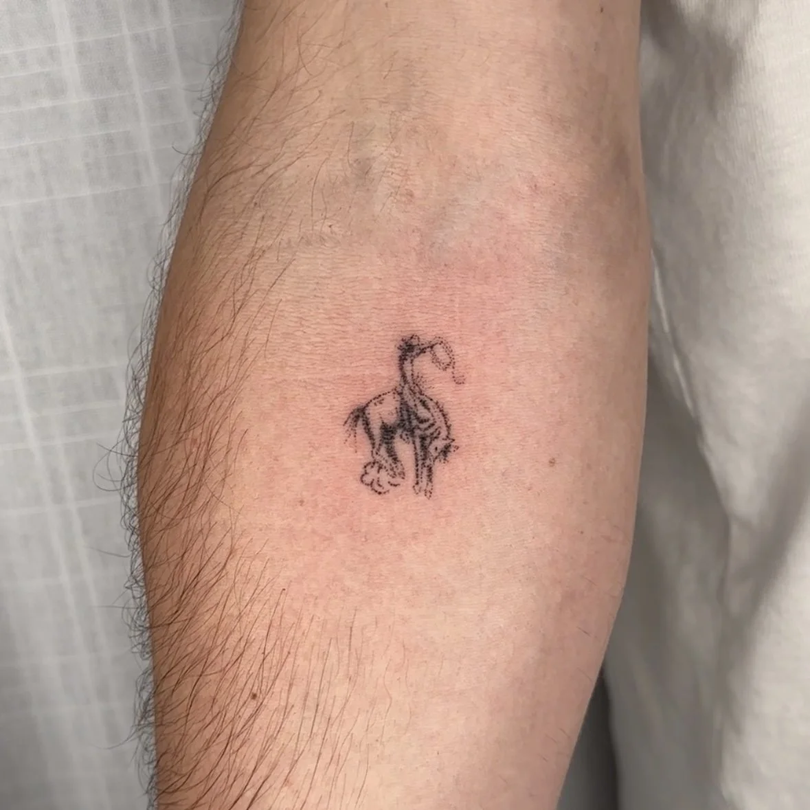 Small tattoo of a cowboy on a person's arm.