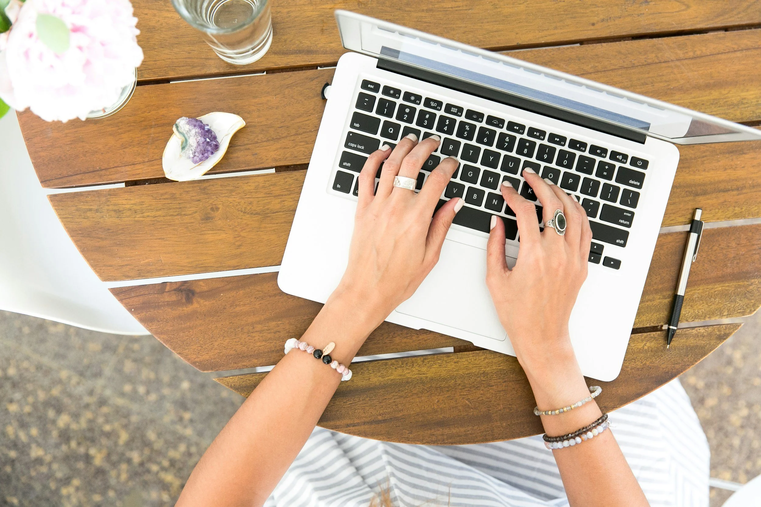 Woman typing on computer outdoors on wooden table