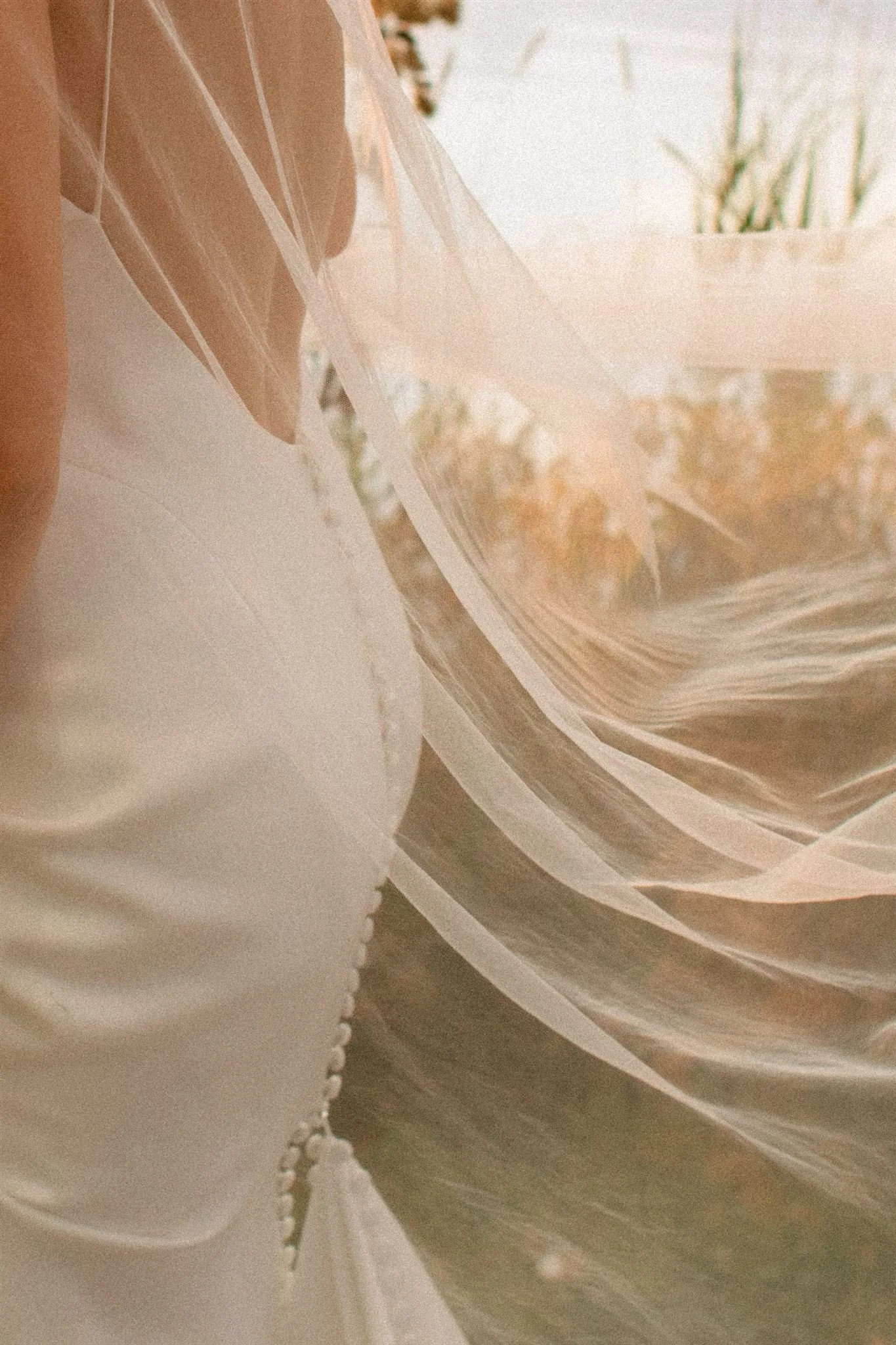 Bride’s wedding dress back button detail and veil by Bisou Bridal in soft sunset light at Northridge Inn