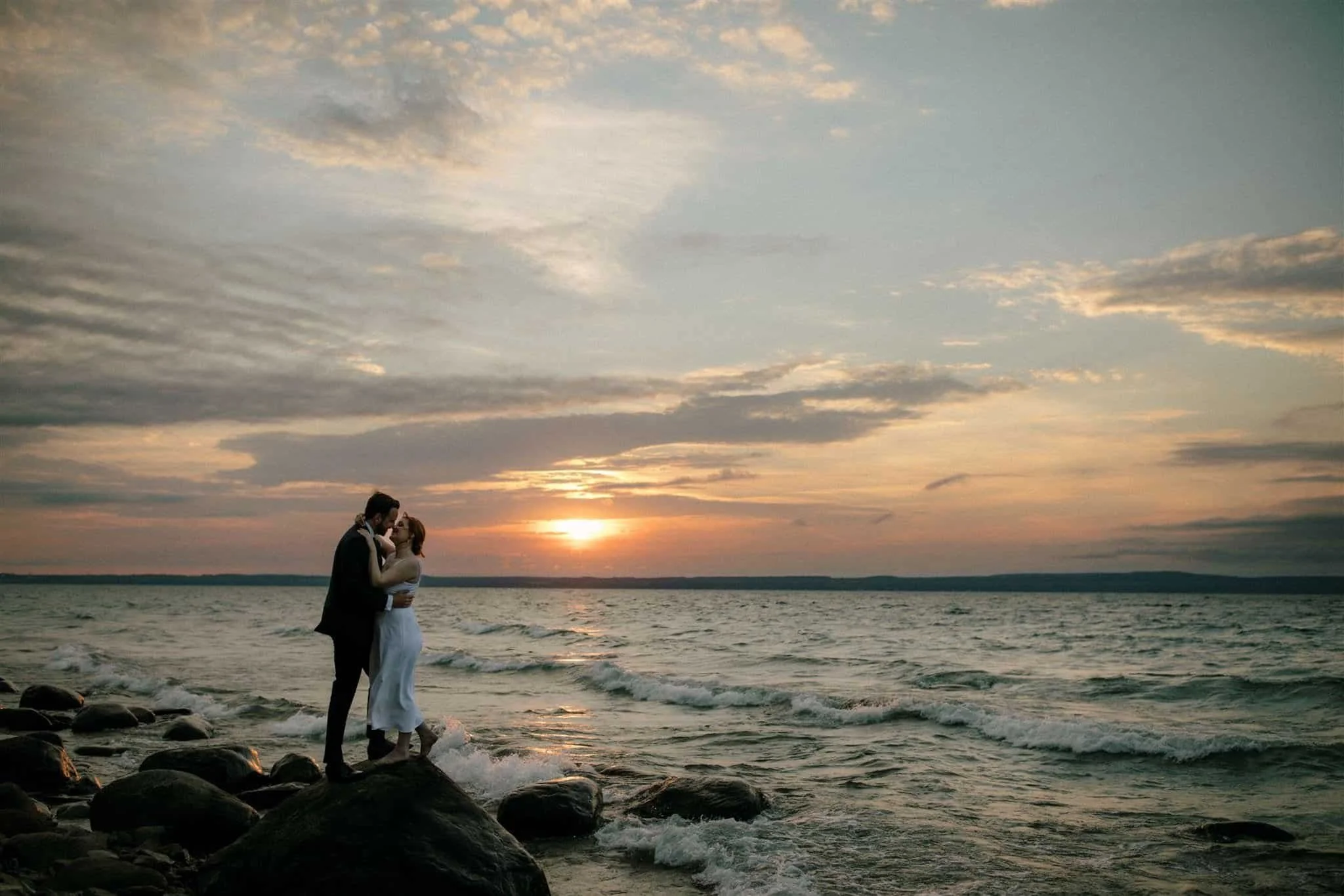 Moody portrait of bride and groom embracing on the shores of Georgian Bay at sunset at Serenity Cottage