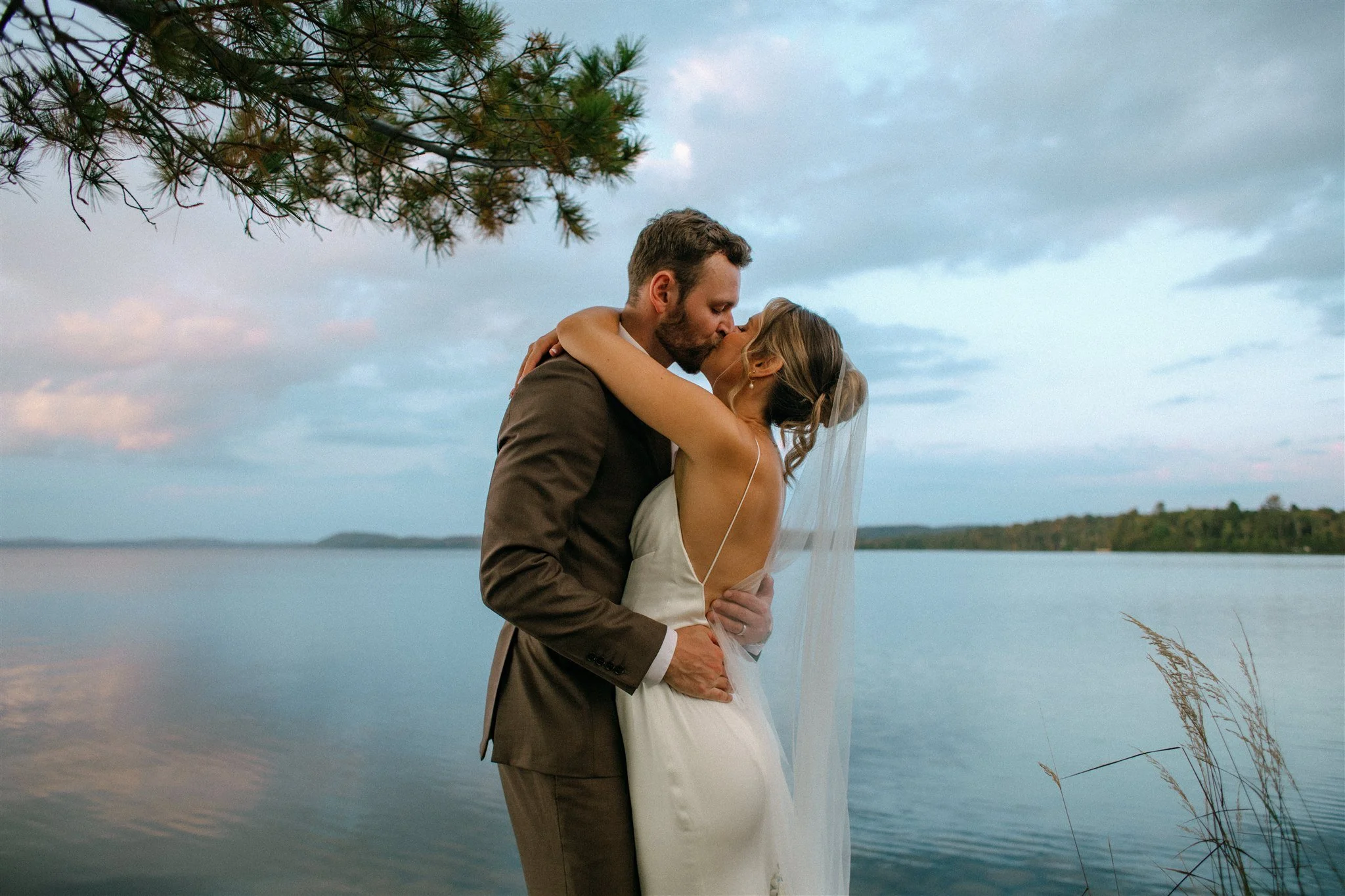 Couple kissing on lake during sunset at Northridge Inn summer wedding