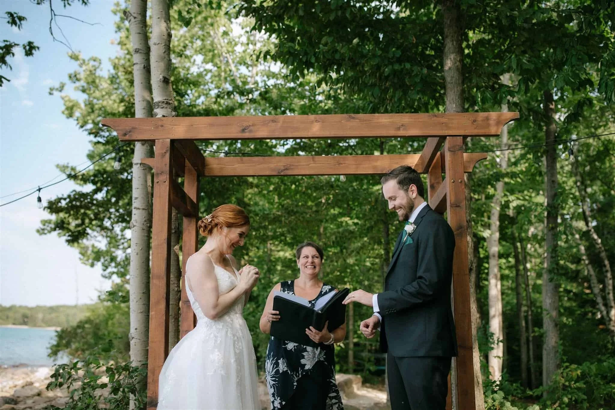 Bride and groom look at wedding rings at outdoor wedding ceremony at Serenity Cottage