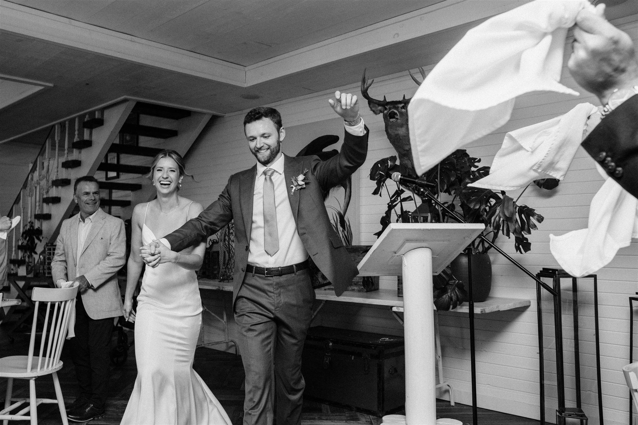 Couple enter Northridge Inn main lodge for their wedding reception with guests waving napkins