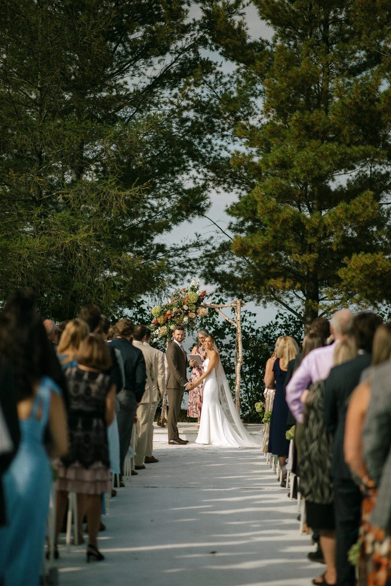 Wedding ceremony on a dock in the middle of the lake surrounded by tall pines at Northridge Inn