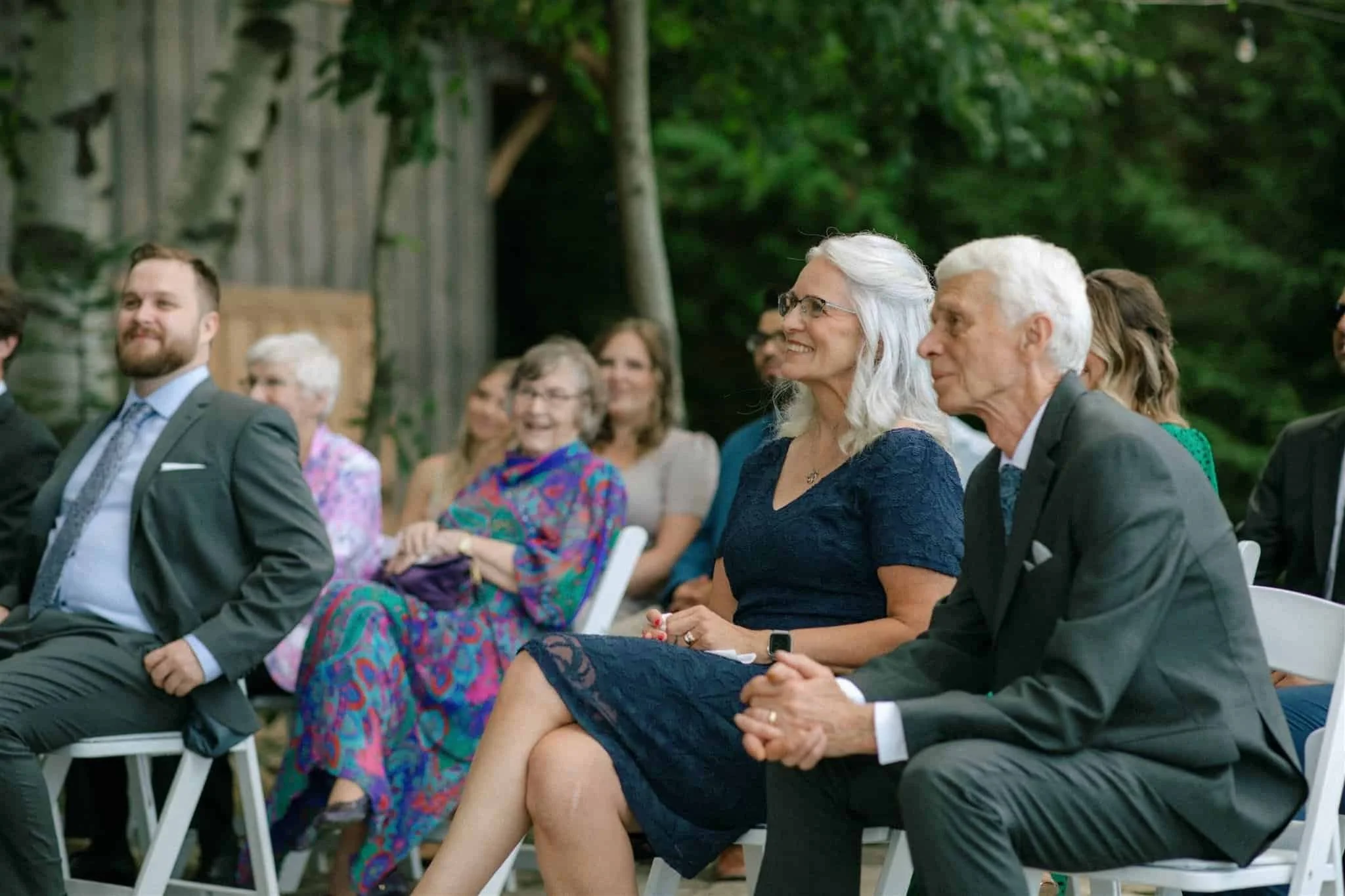 Groom's parents beaming during the outdoor wedding ceremony