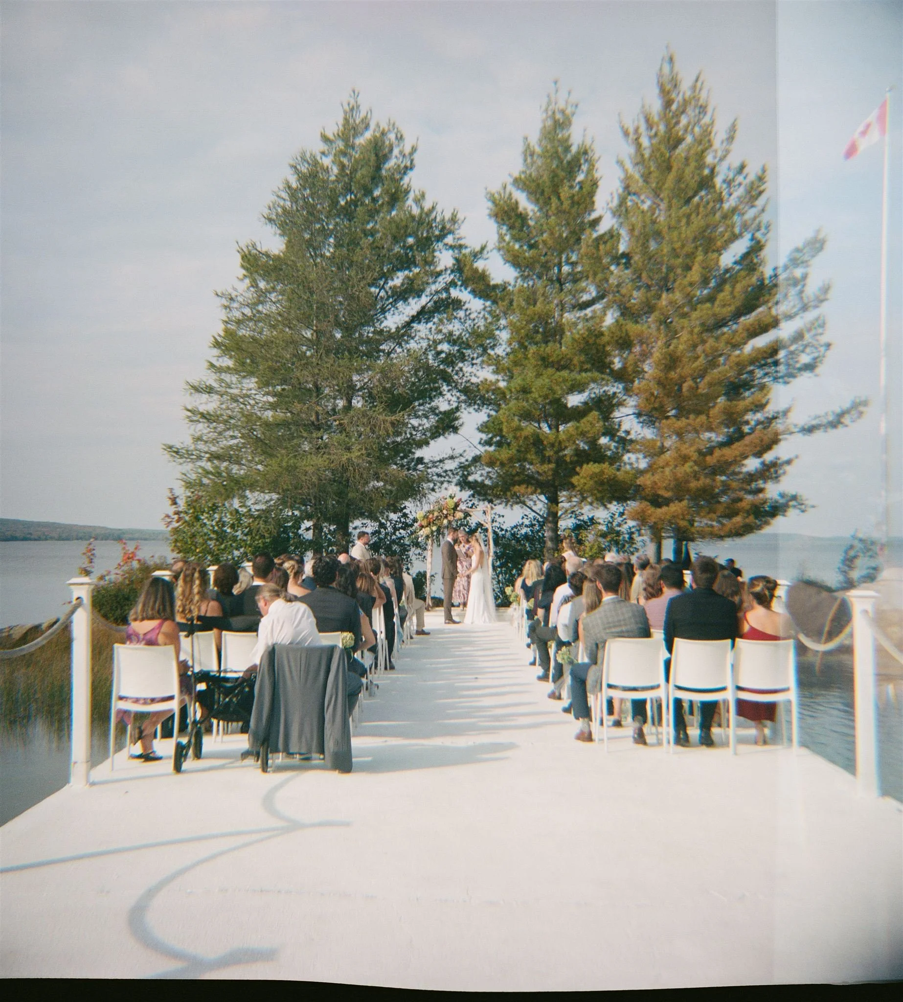 Wedding ceremony on a dock in the middle of the lake surrounded by tall pines at Northridge Inn shot on film