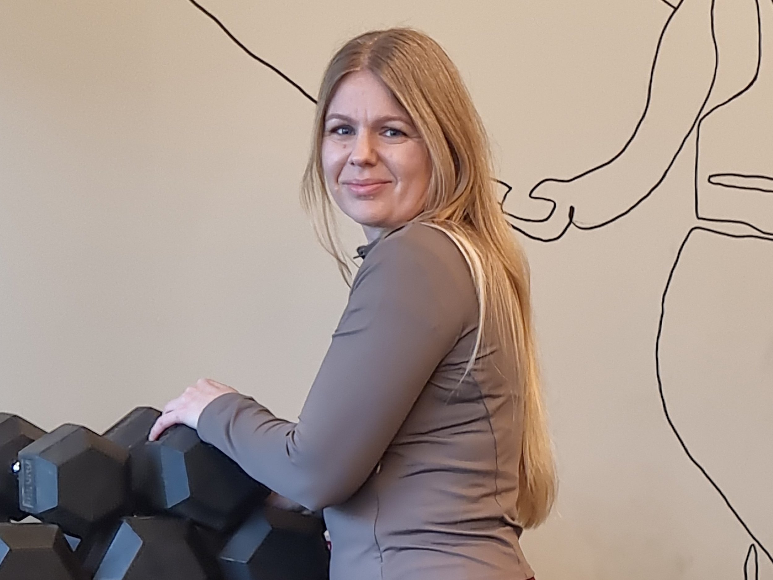 Leende, kvinnlig personlig tränare vid hantlar