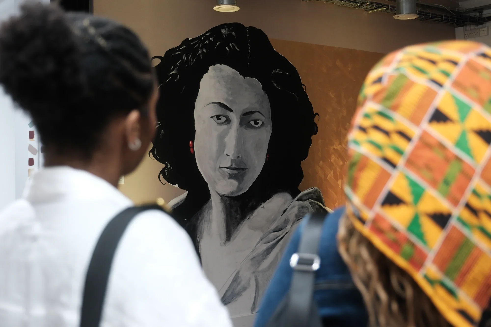 Two visitors gaze at a mural of Sarah Bernhardt and she gazes back