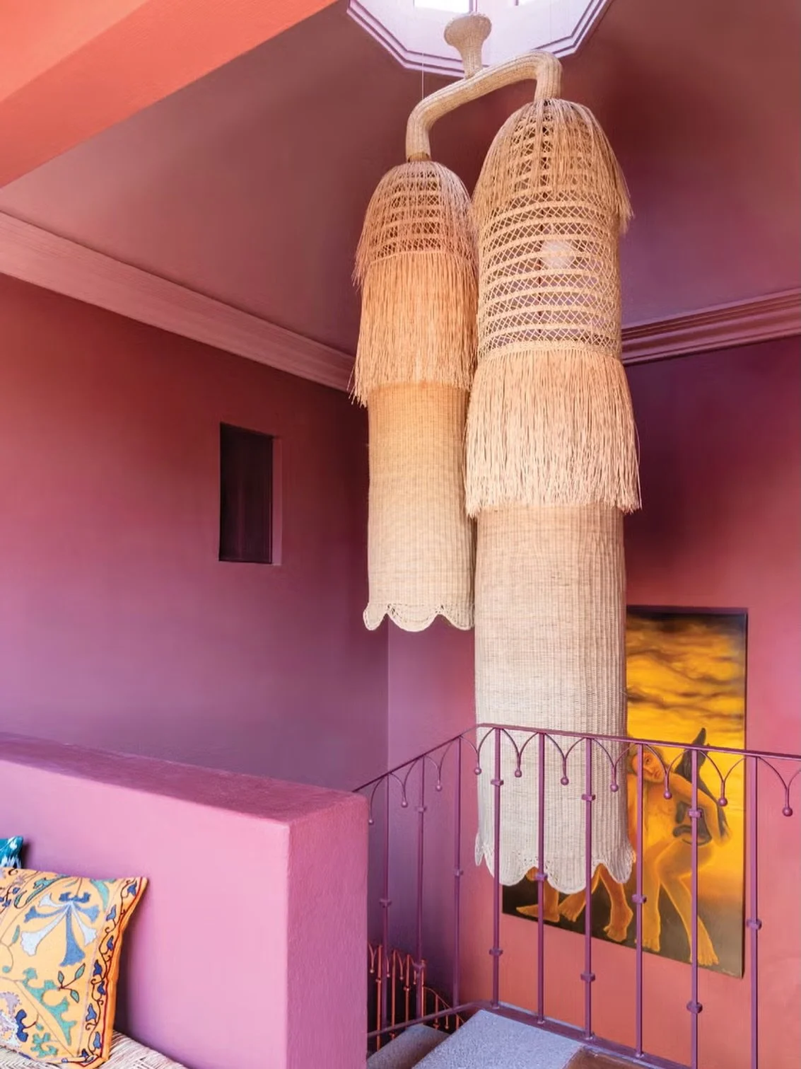 Color is a decision made by hand.

These pendants weren&rsquo;t ordered from a catalog &mdash; they were woven, fringed, hung by someone who understood that light should arrive soft. Plum walls, a railing painted to match, a painting that refuses to 
