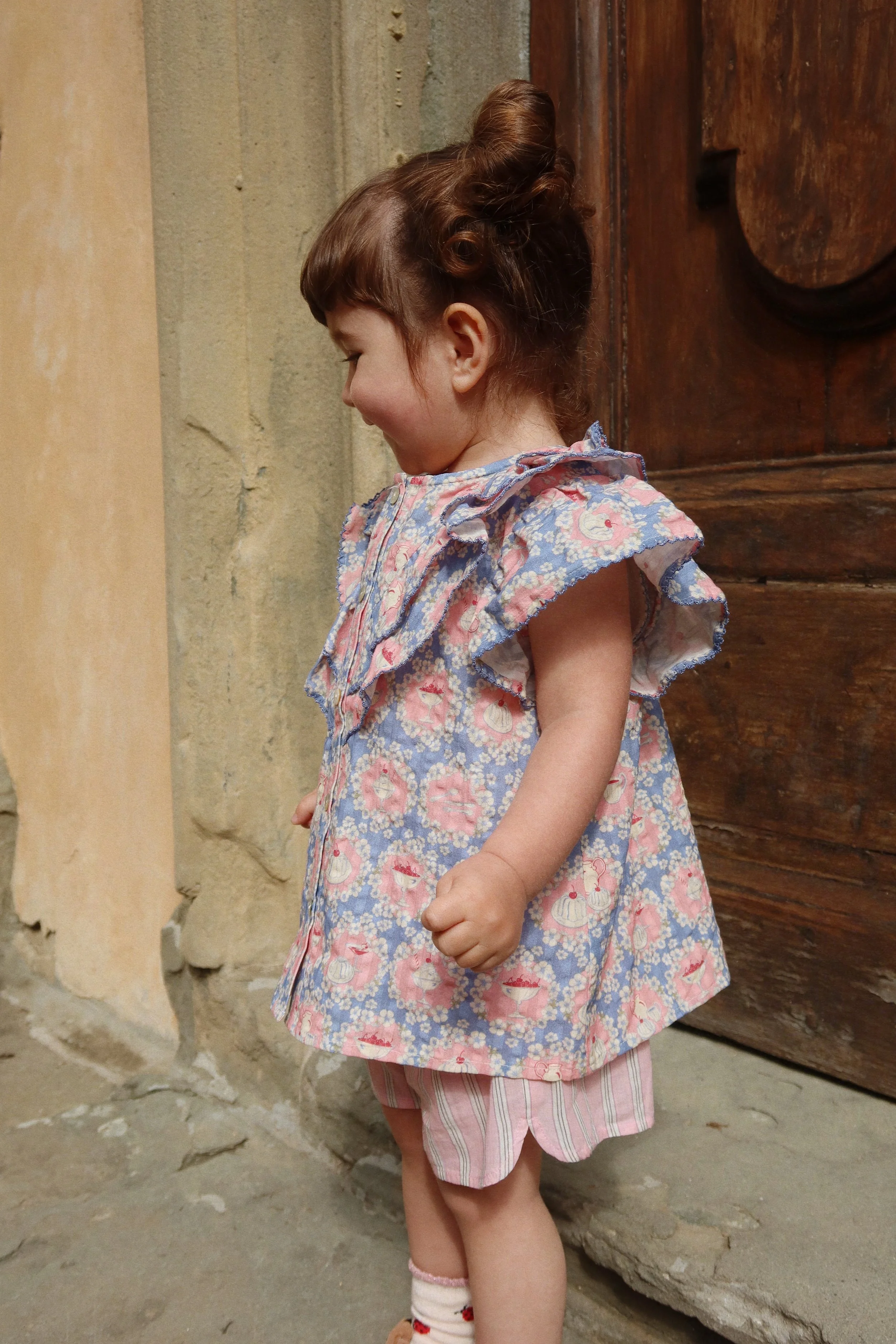 Weißes Kinder T-Shirt aus Bio-Baumwolle mit Rüschendetails und verspieltem Snack Time Print im Kids Concept Store Cleo&Caesar.