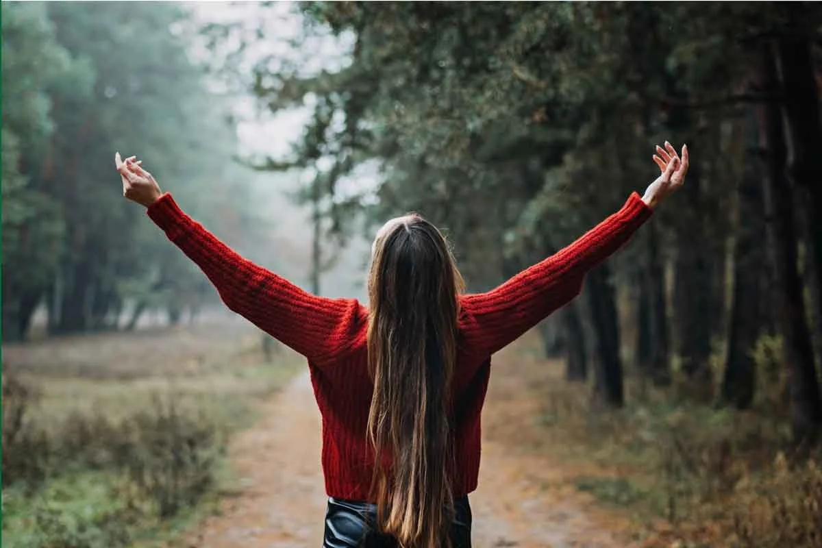 Woman holding her arms aloft in nature