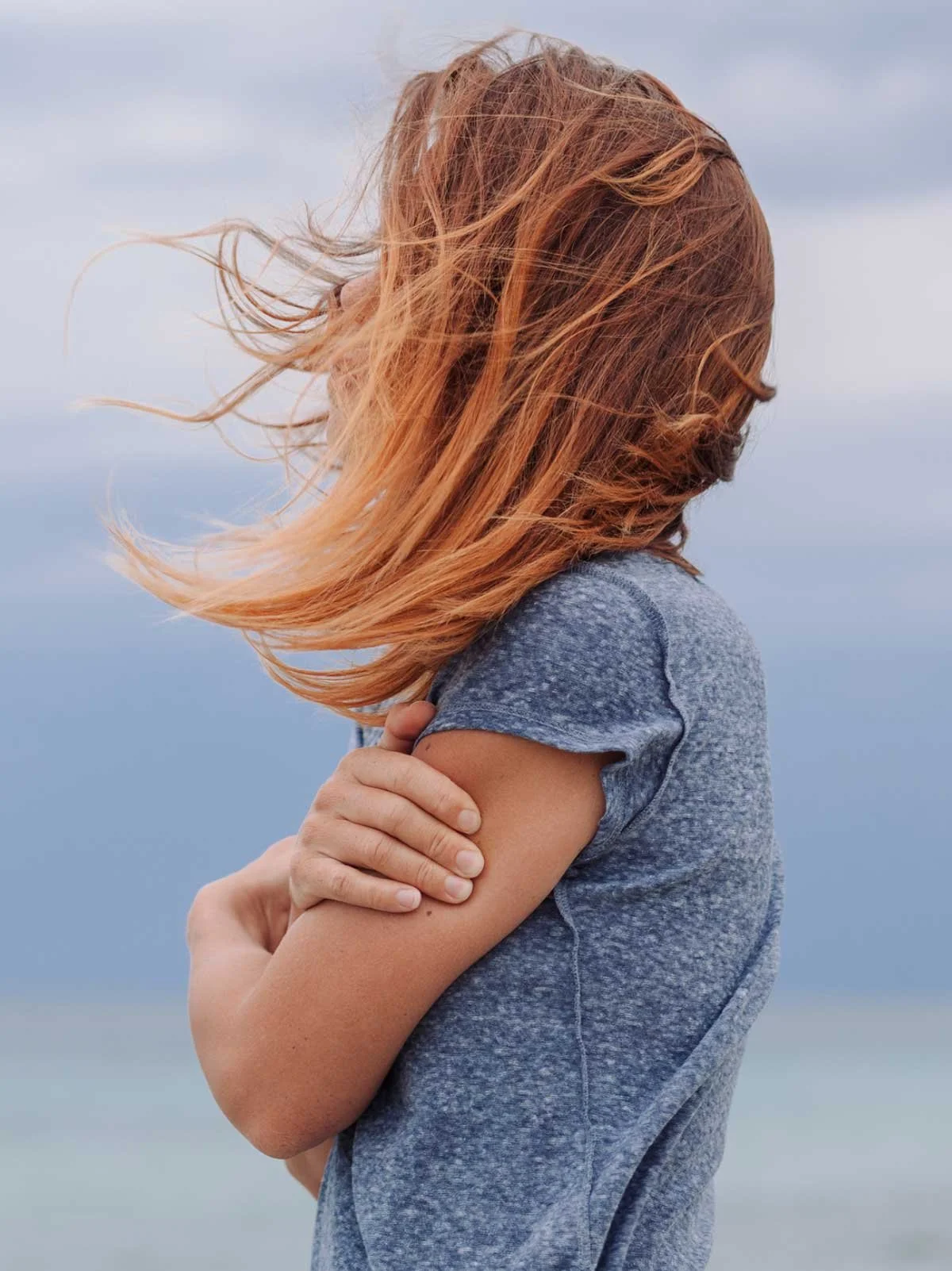 Woman standing gripping her own arms
