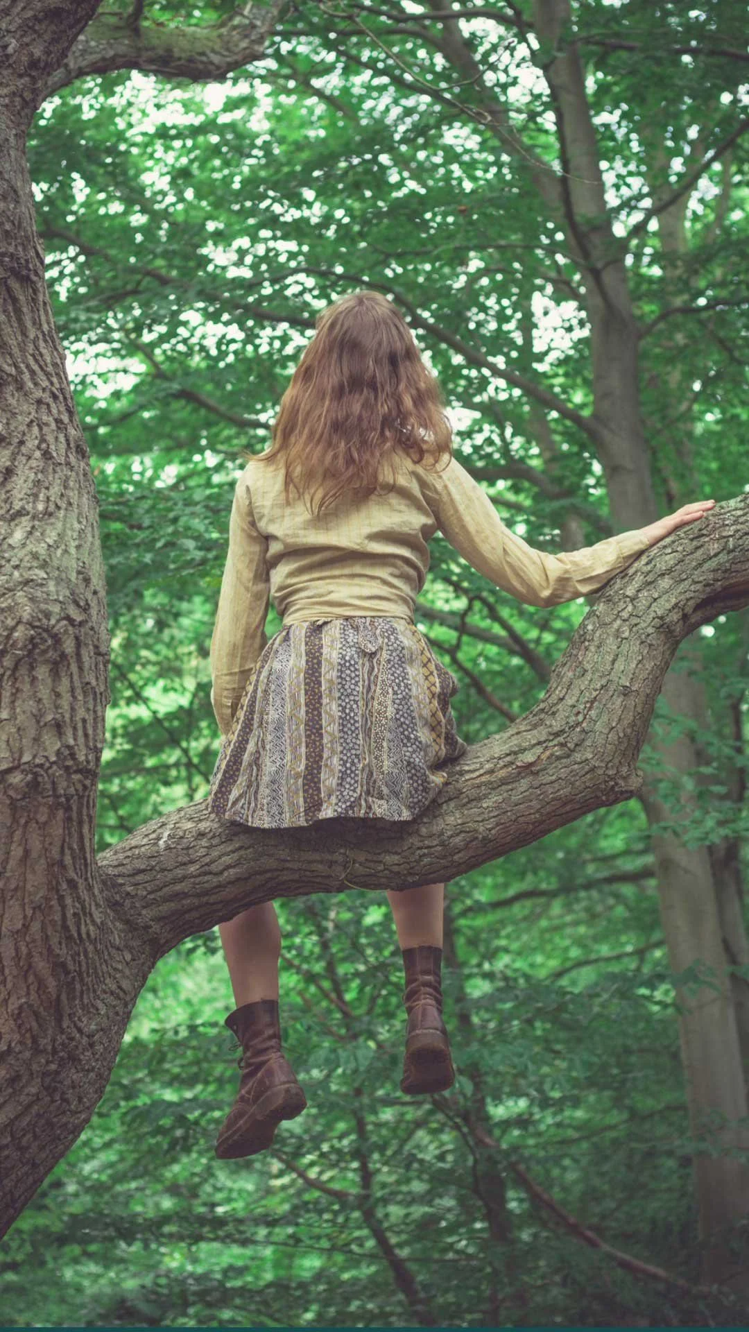 Young woman sitting in a tree