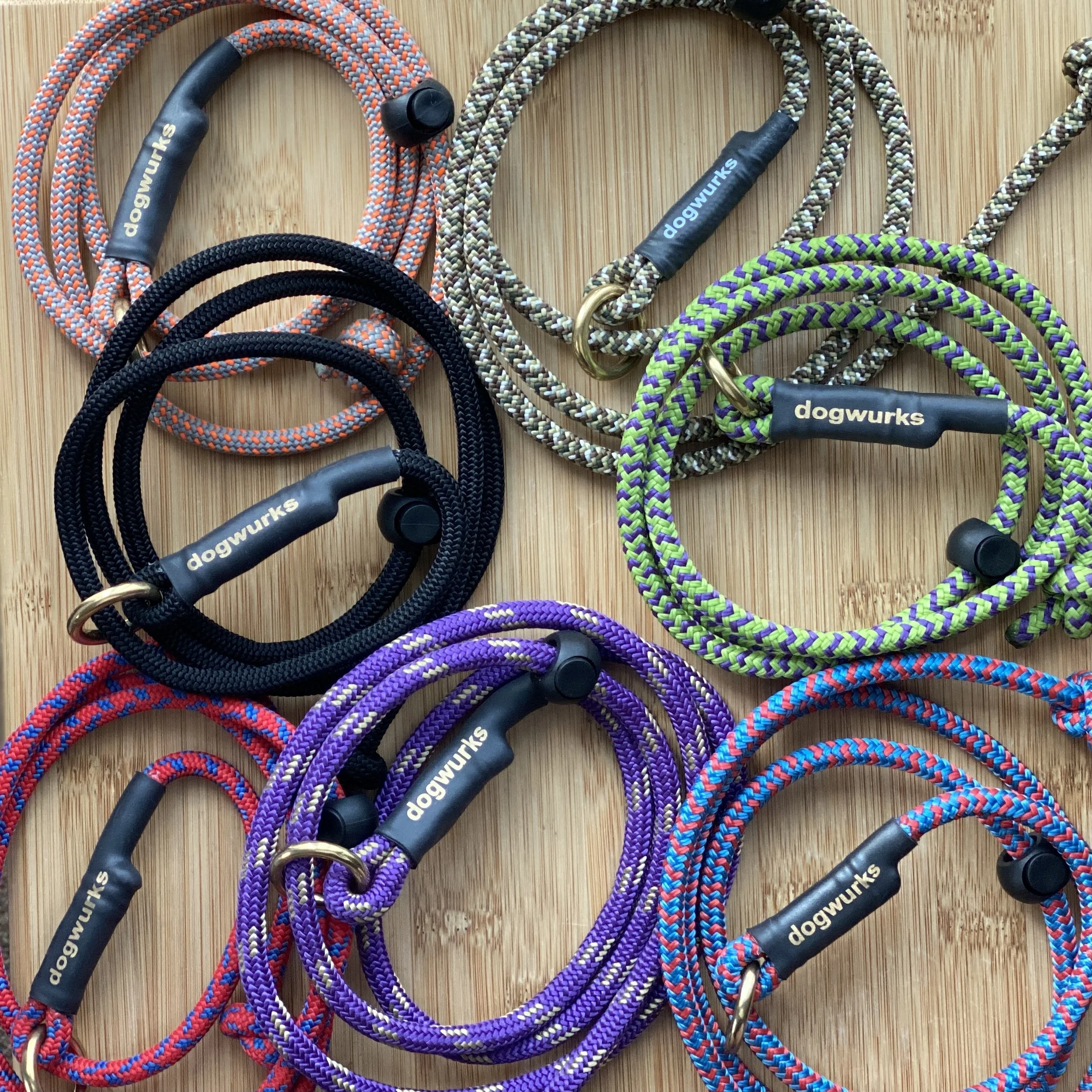 A collection of colorful dog leashes with black handles on a wooden surface.