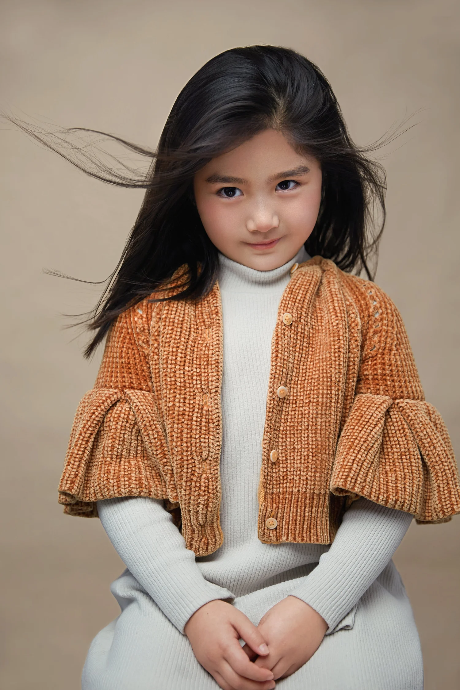 Little girl in a cream sweater and caramel cardigan