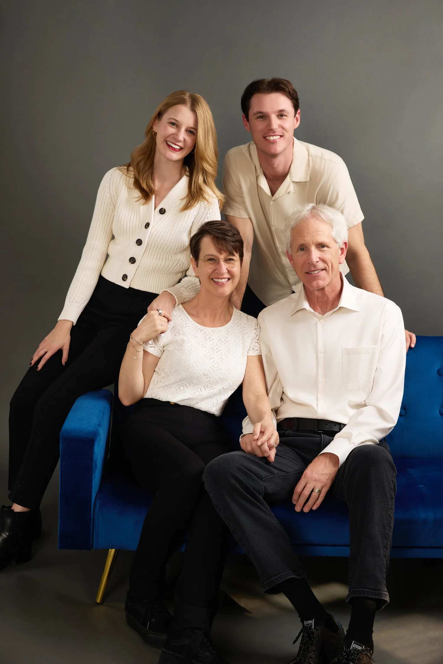 Parents and their grown children together on a velvet sofa