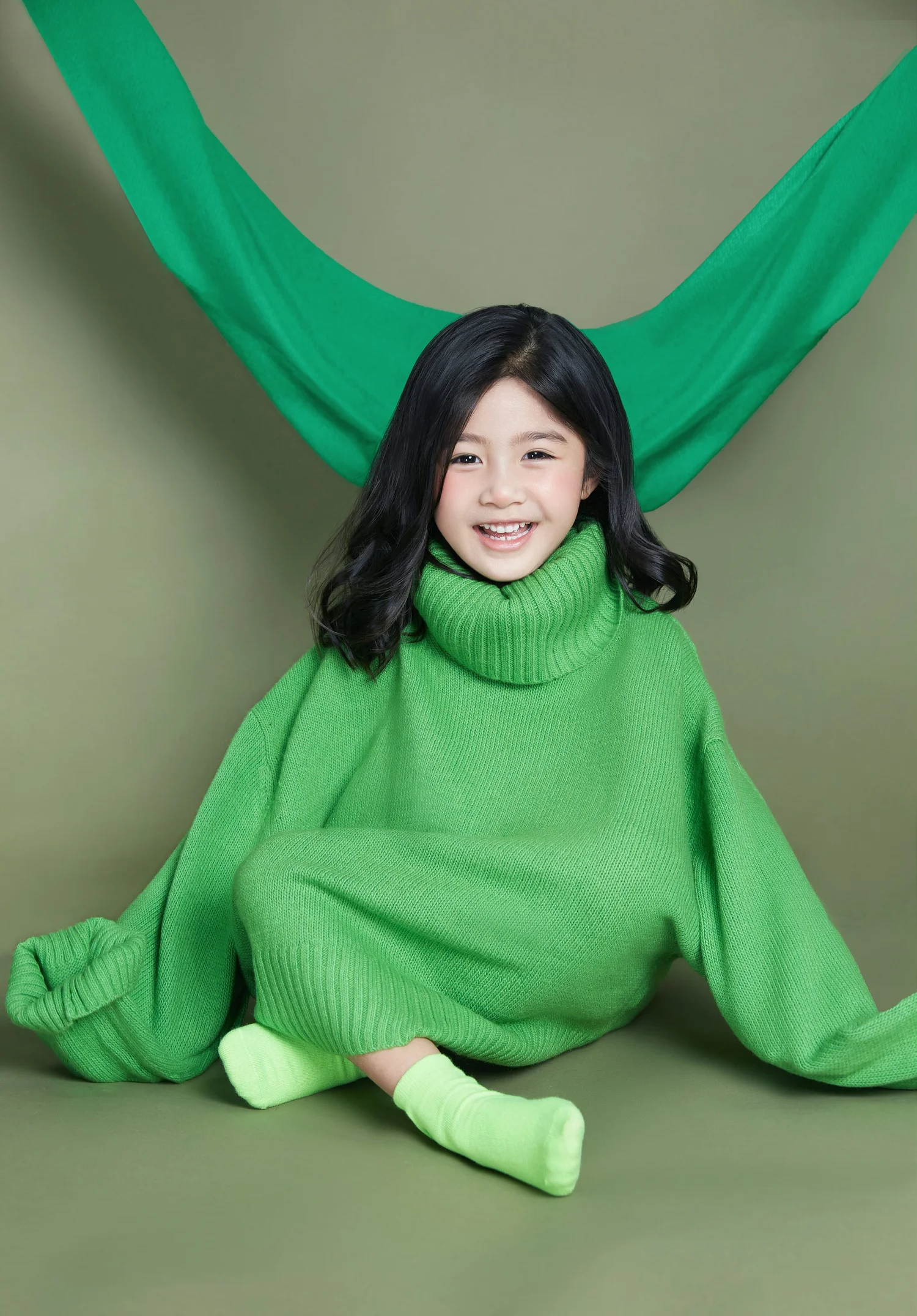 Girl in a green sweater under a green drape