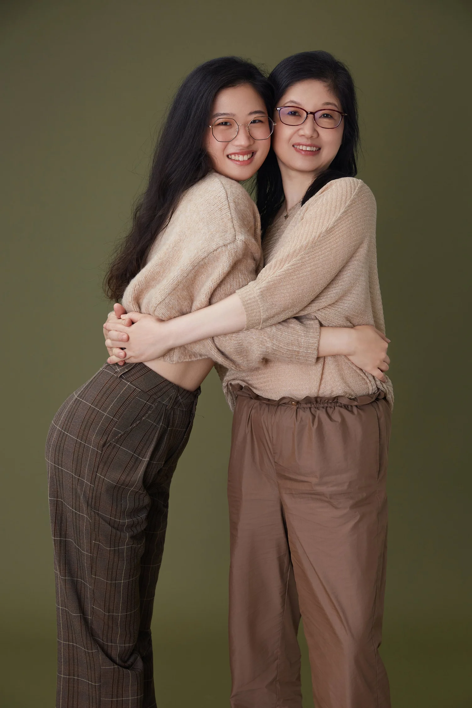 Mother and adult daughter embracing, olive green background — Luminous Space portrait