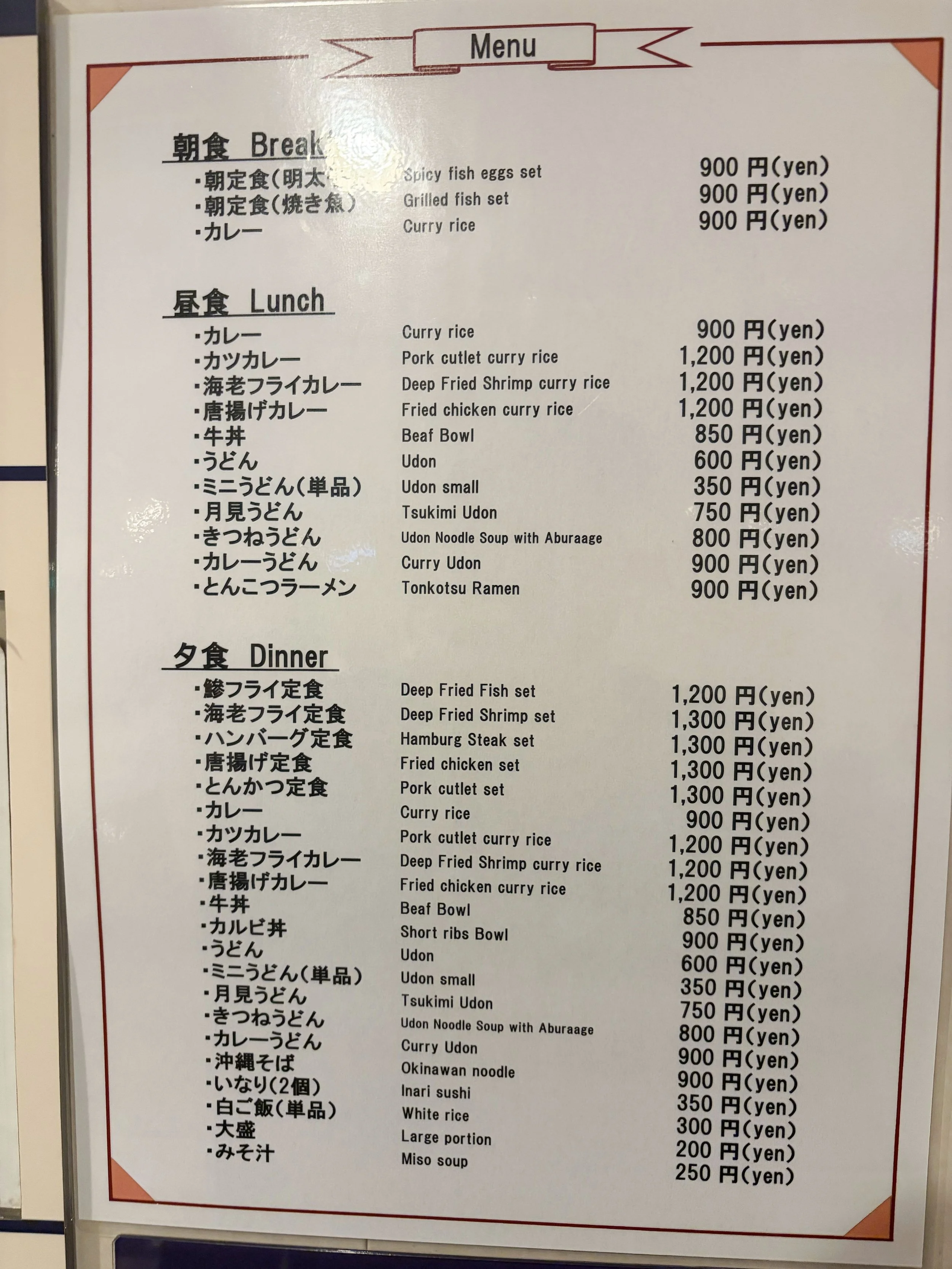 白い背景に赤い縁取りが施された飲食店のメニュー表です。上から朝食、昼食、夕食に分かれ、日本語と英語で料理名が並んでいます。カレーやうどん、牛丼、ラーメン、定食など種類が豊富で、価格は350円から1300円程度。右側にそれぞれの料金が表示されています。