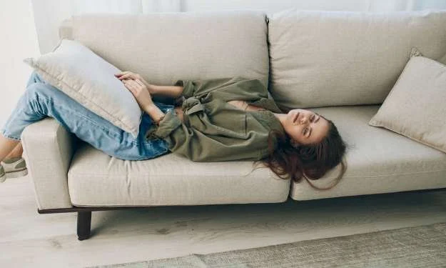 Frau liegt nachdenklich auf dem Sofa und fühlt sich emotional erschöpft in einer schwierigen Beziehung