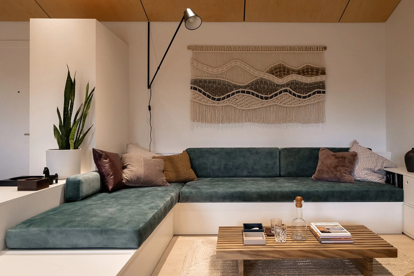 custom-corner-couch-and-storage-with-blue-velvet-upholstery-slatted-wood-coffee-table-wool-wall-hanging.jpg