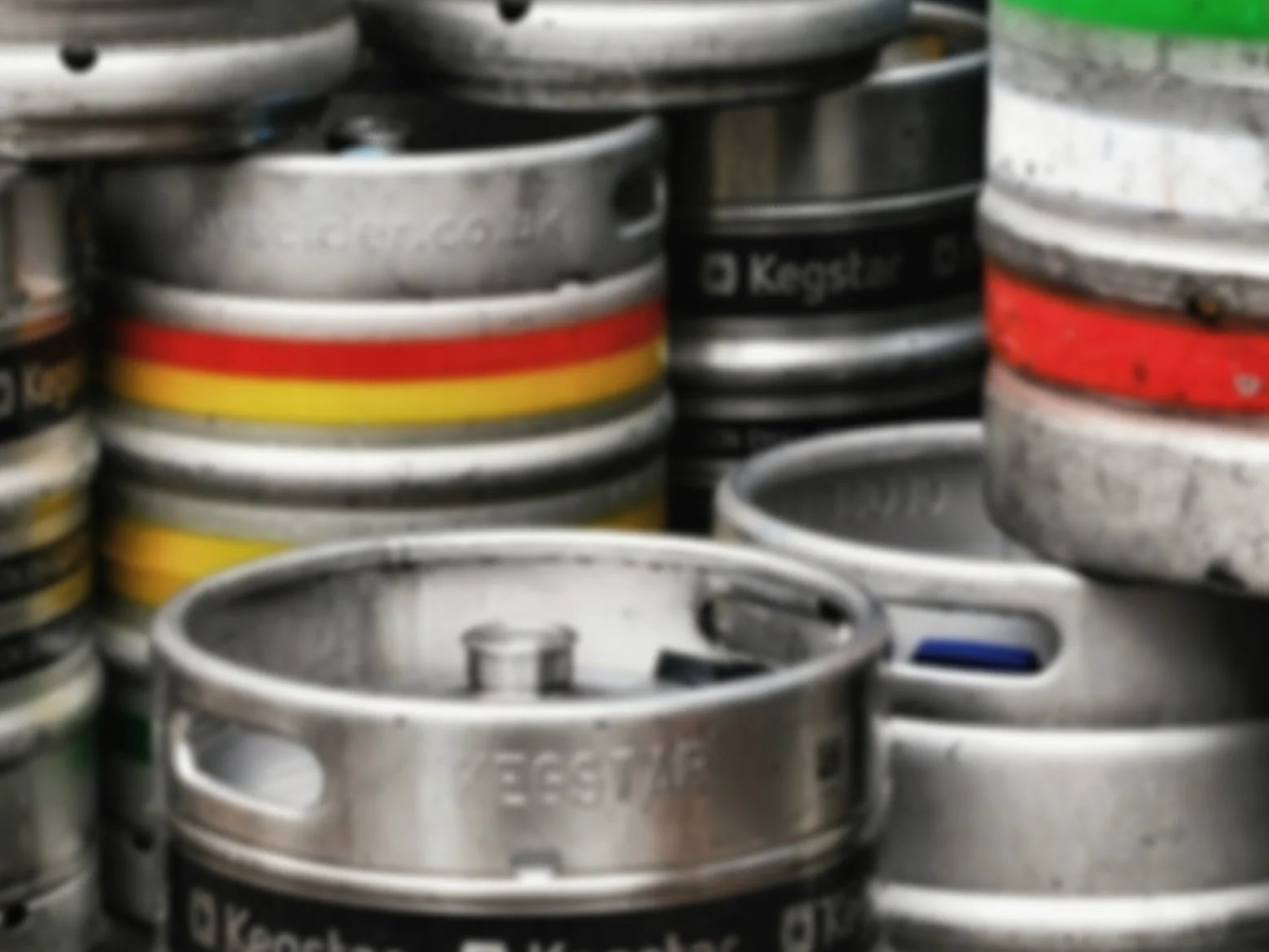 Stack of aluminum beer kegs with various colored bands